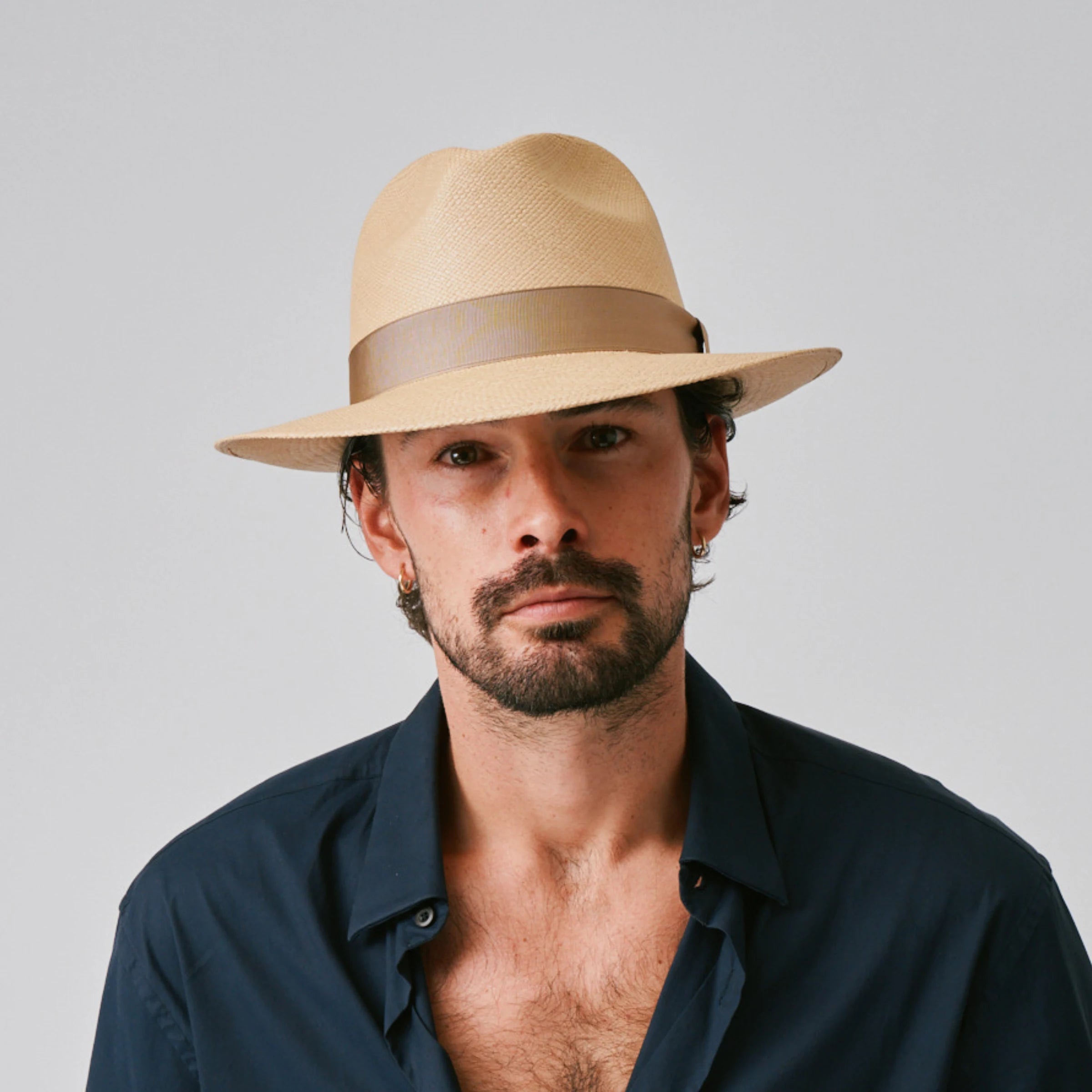 Man wearing a Camilo Classic Sand / Taupe Panama hat and navy shirt against a plain background.
