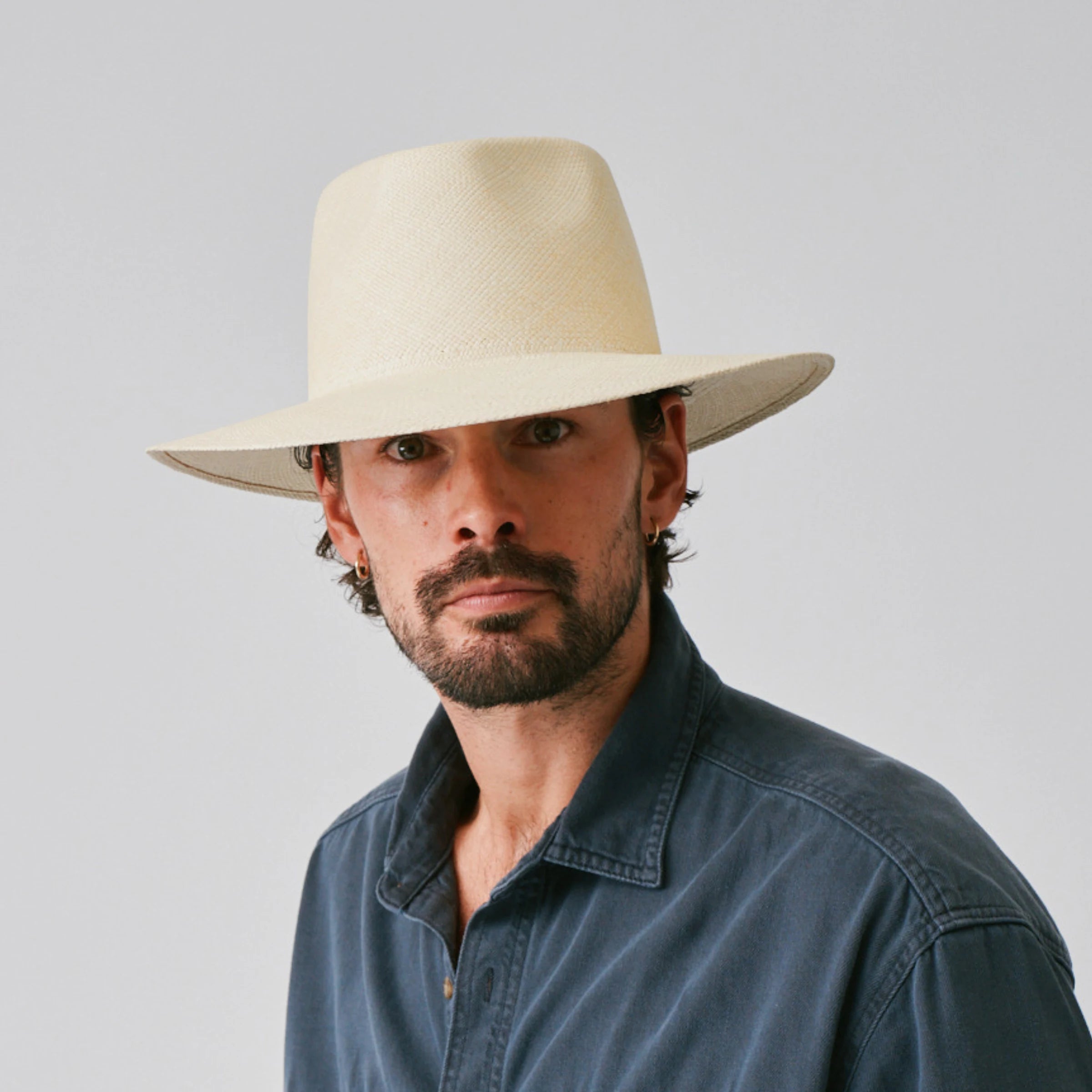 Man wearing a Country Natural Panama hat and blue shirt against a plain background.