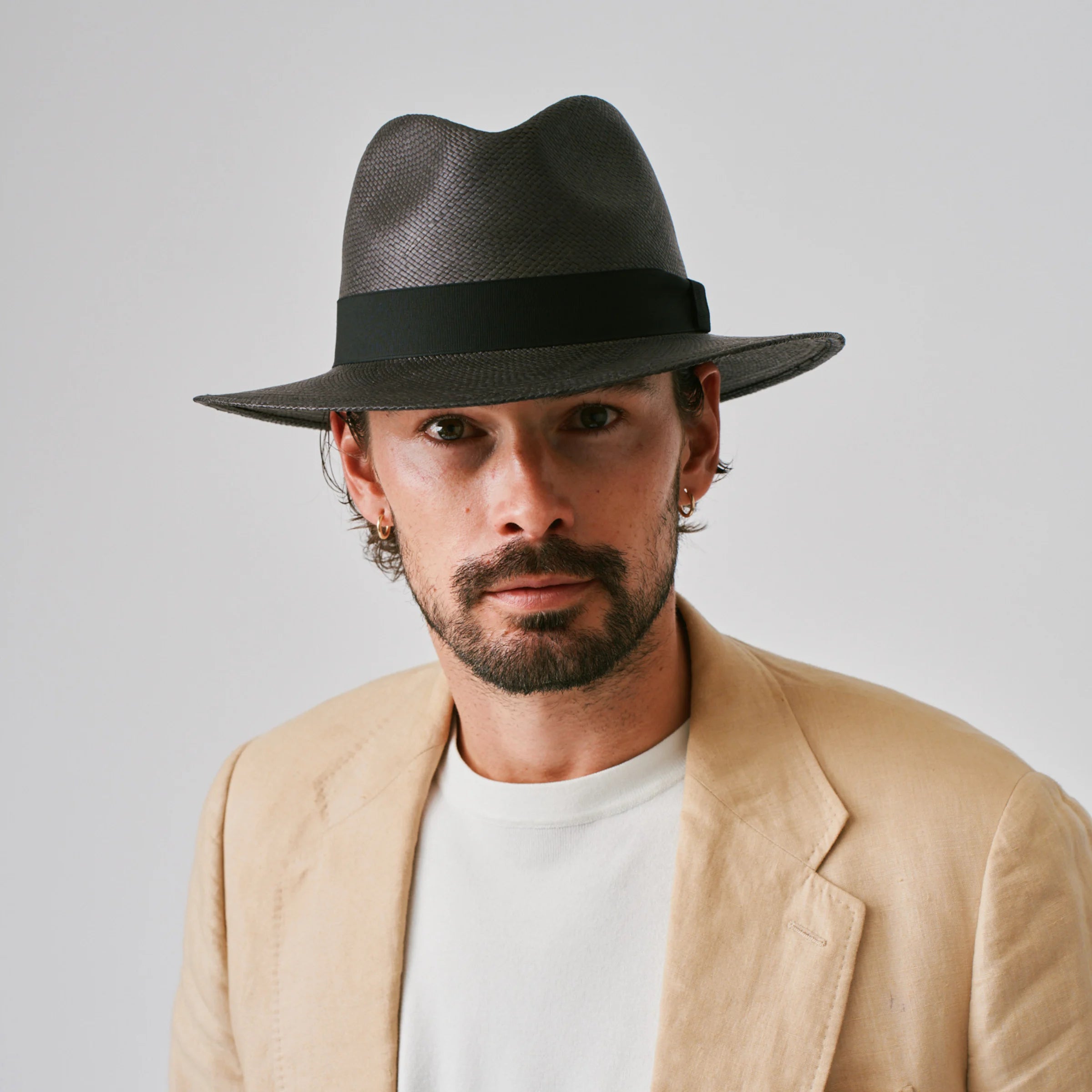Man wearing a Executive Black / Black Panama hat and linen suit jacket against a plain background.