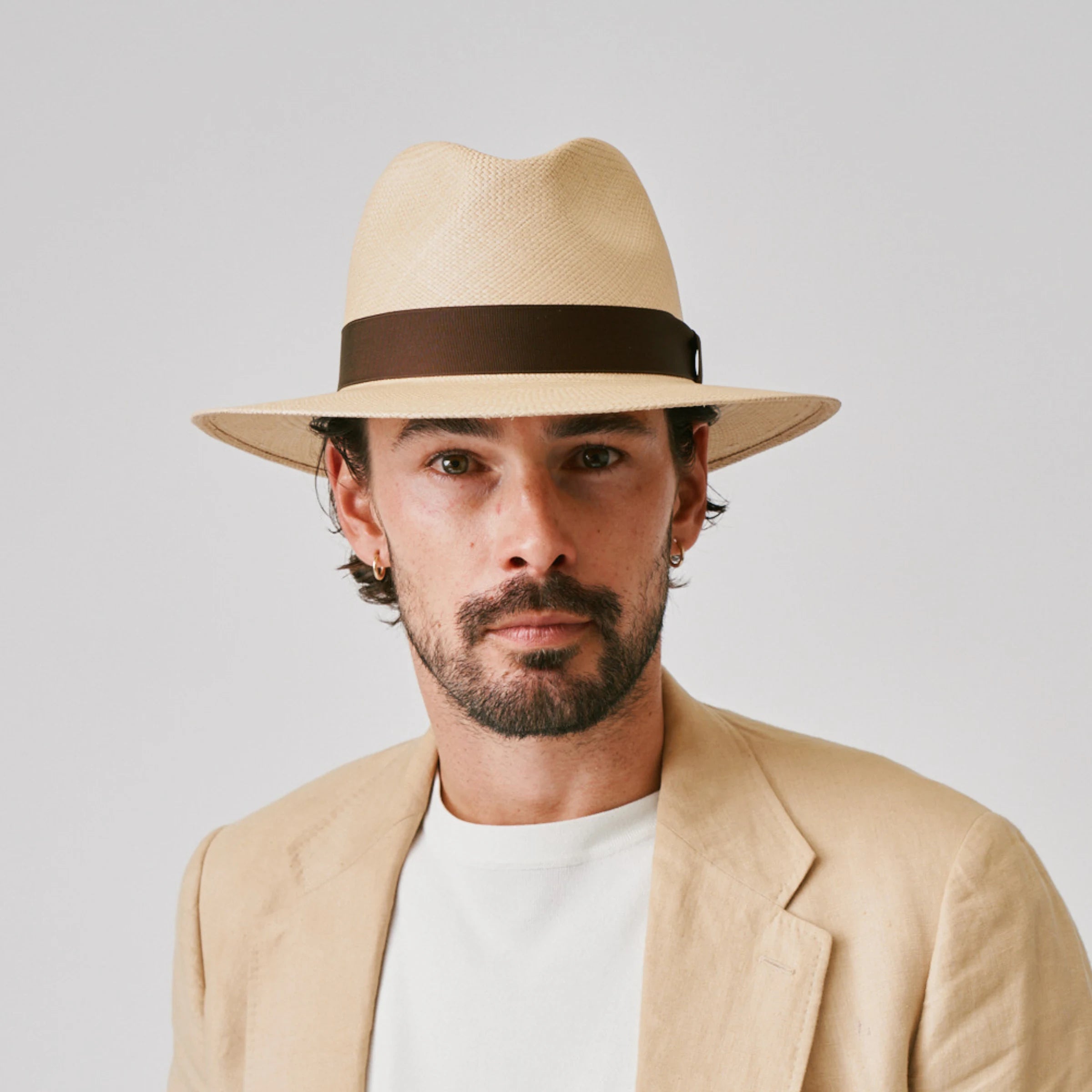 Man wearing a Executive Sand / Caffe Panama hat and linen jacket against a plain background.
