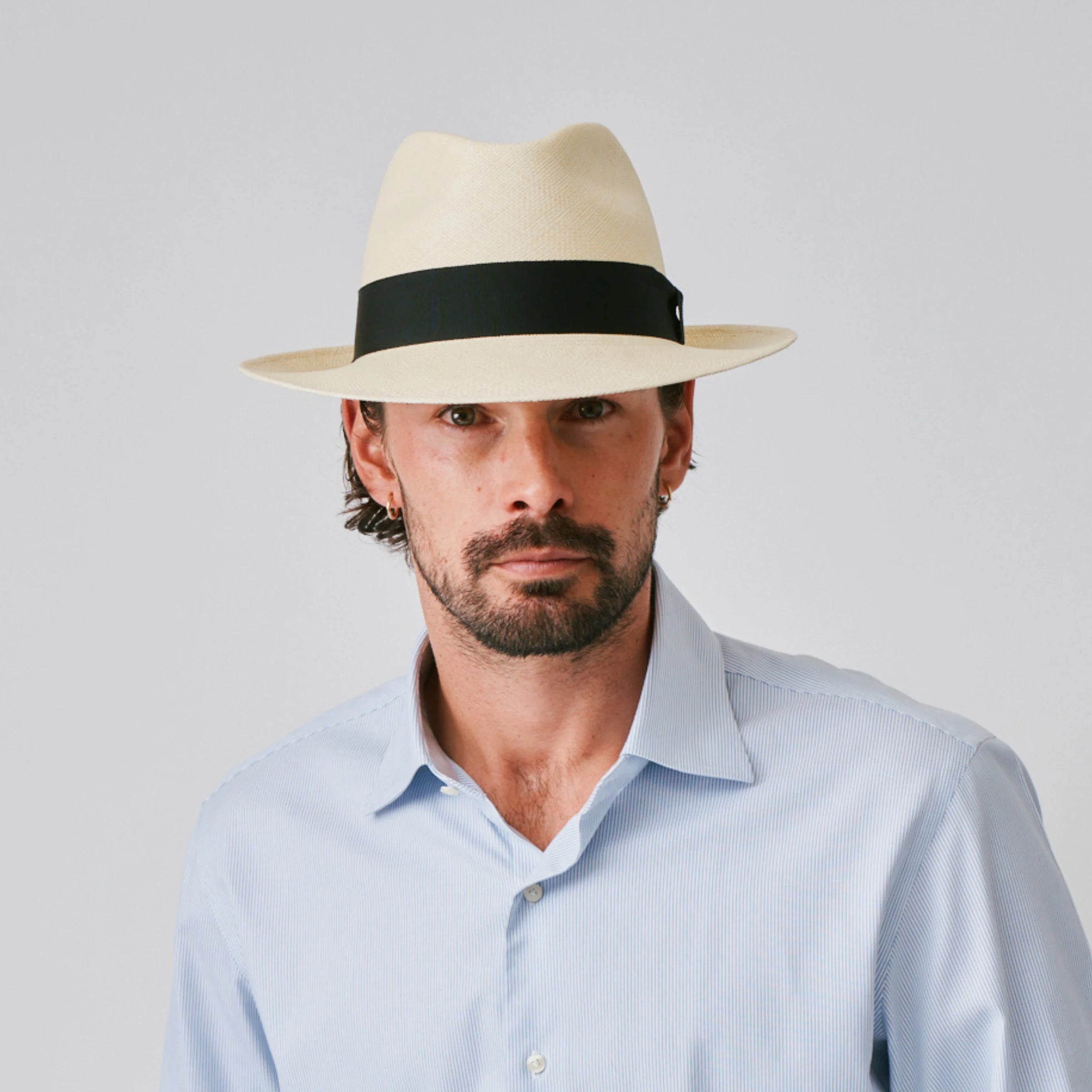 Man wearing a New Fedora Fino Natural / Black Panama hat and blue shirt against a plain background.