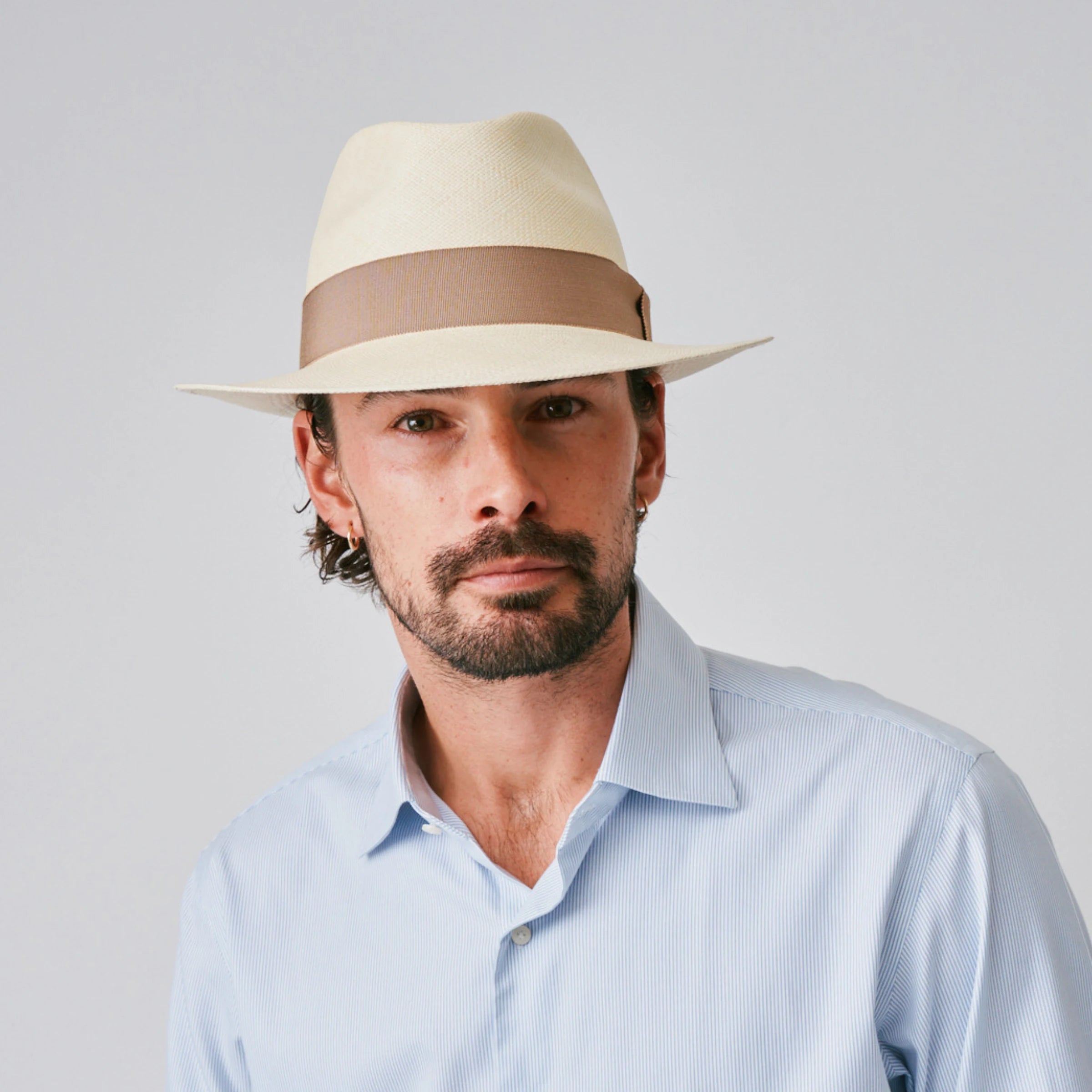 Man wearing a New Fedora Fino Natural / Oat Panama hat and blue shirt against a plain background.