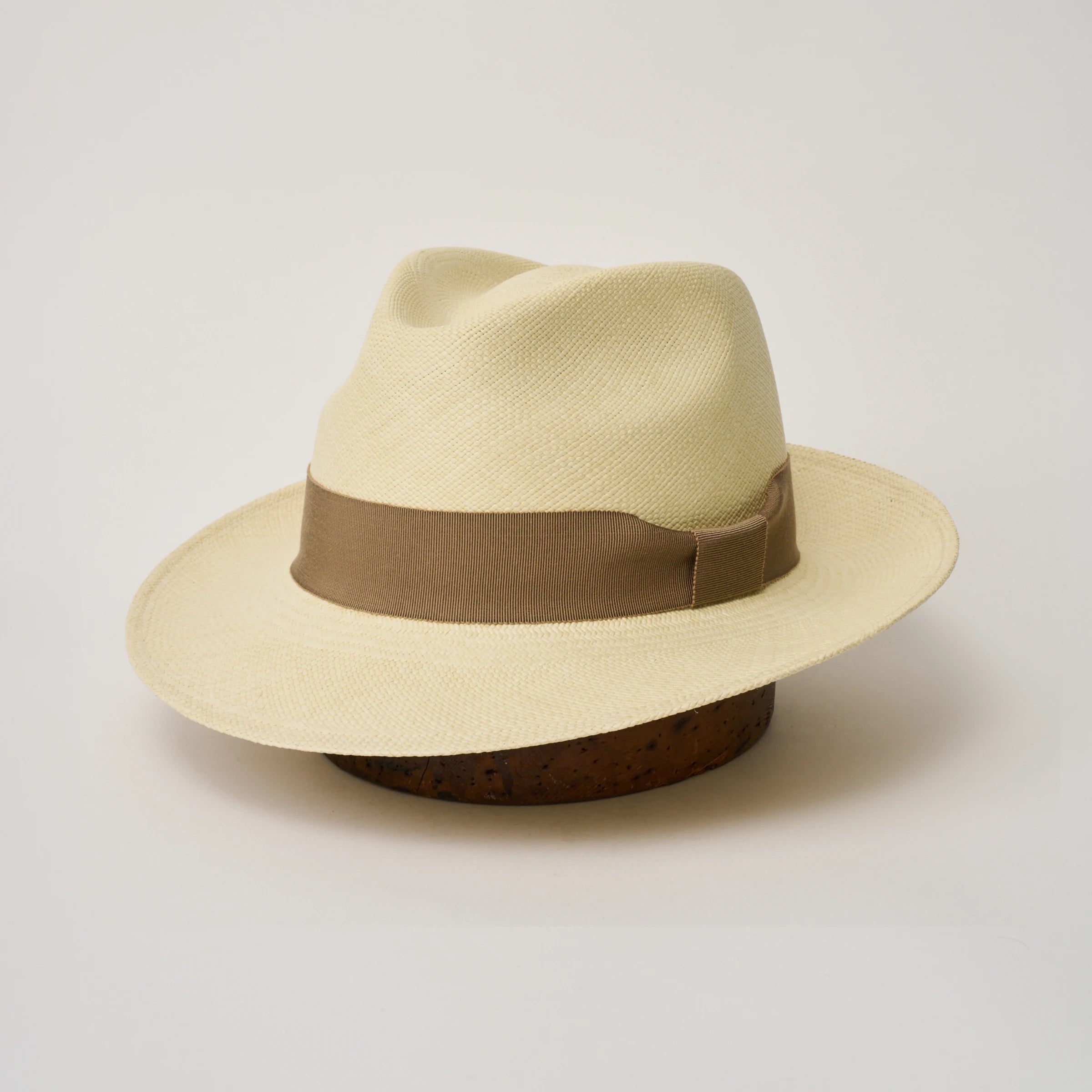 Studio image, three-quarter view of the Camilo New Fedora Fino Natural coloured Panama Hat with Oat trim, showing the crown shape, front crease and ribbon trim.