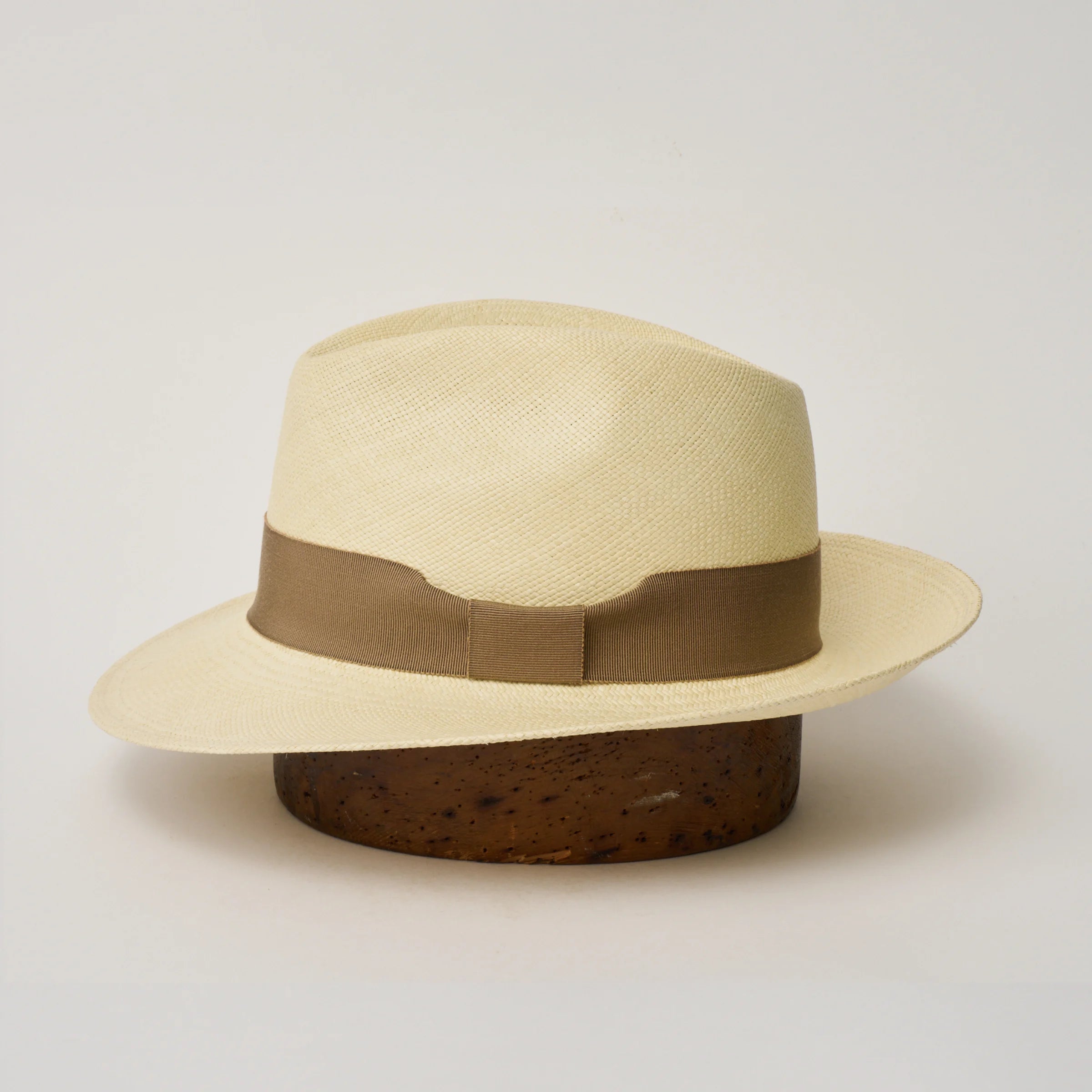 Studio image of the Camilo New Fedora Fino Natural coloured Panama Hat with Oat trim shown from the side, showing the brim shape and ribbon finish.