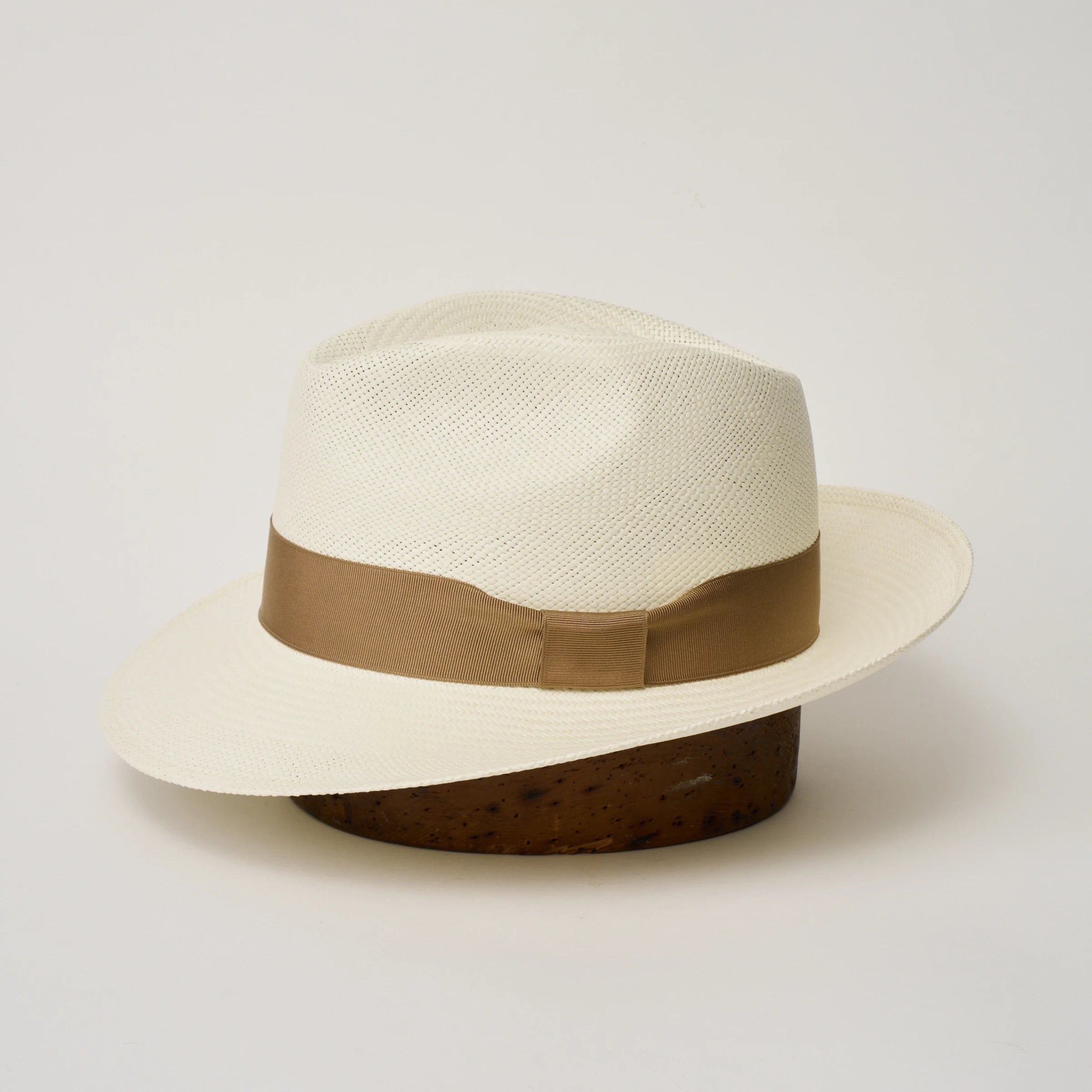 Studio image of the Camilo New Fedora Cream coloured Panama Hat with Tan trim shown from the side, showing the brim shape and ribbon finish.