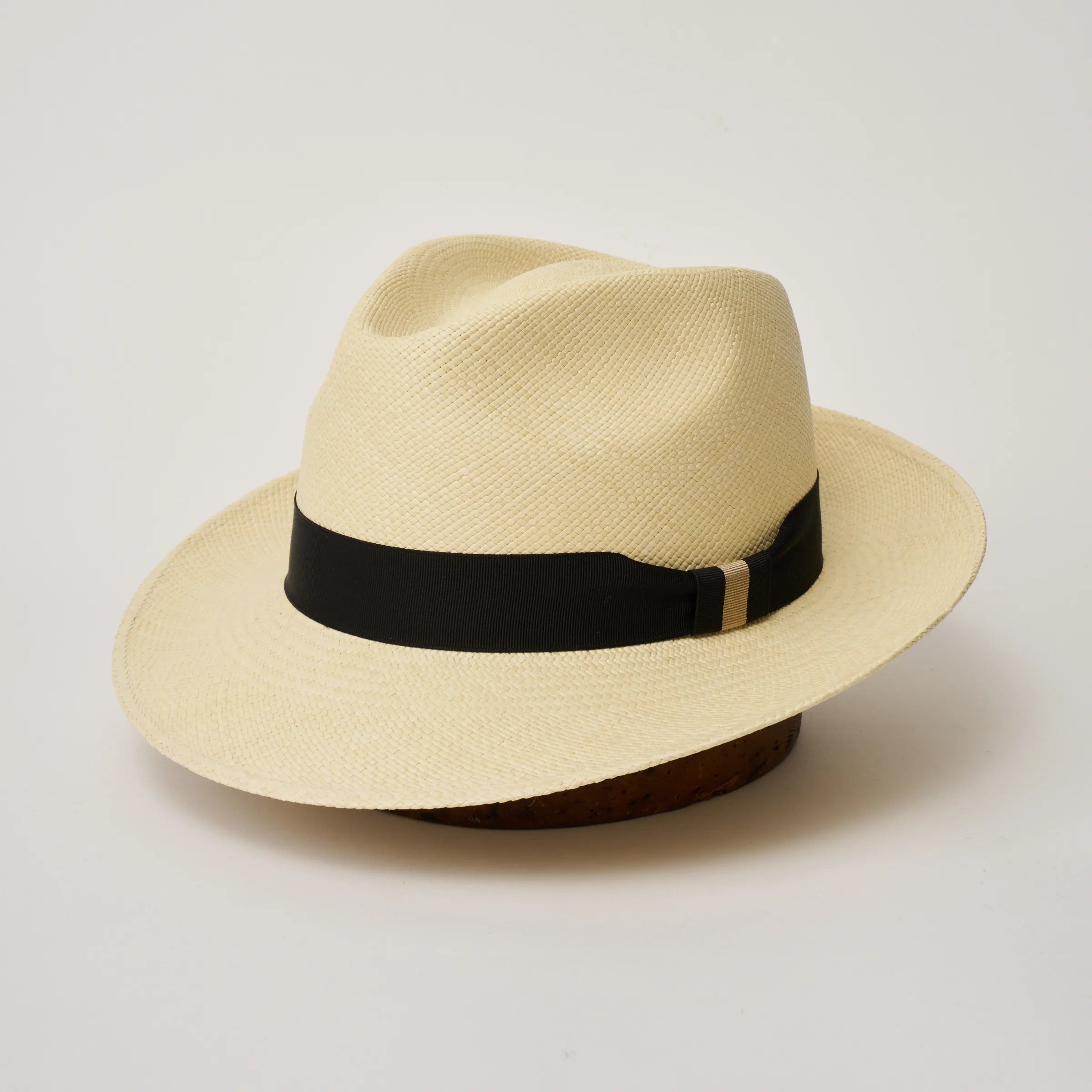 Studio image, three-quarter view of the Camilo New Fedora Natural coloured Panama Hat with Black trim, showing the crown shape, front crease and ribbon trim.