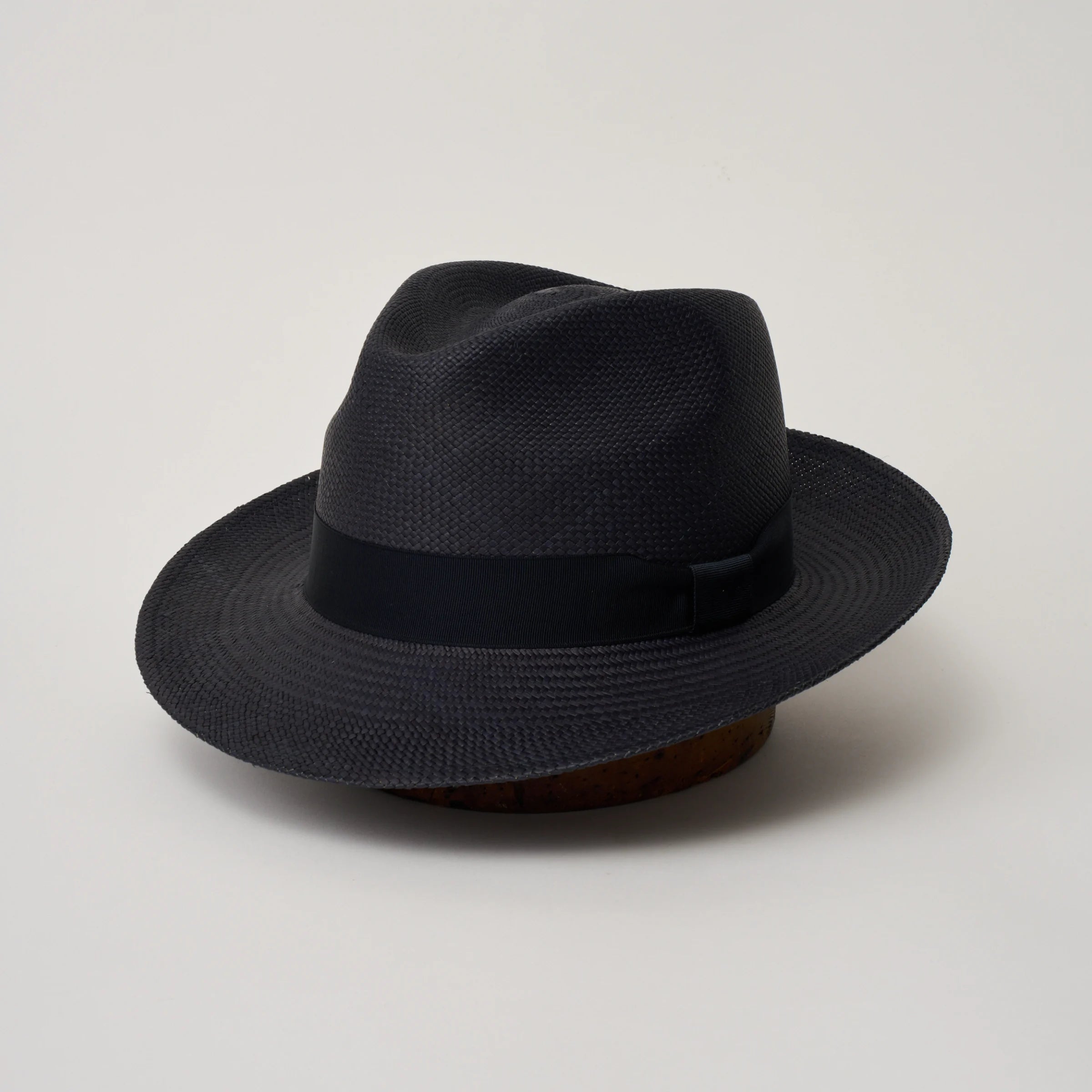 Studio image, three-quarter view of the Camilo New Fedora Navy coloured Panama Hat with Marine trim, showing the crown shape, front crease and ribbon trim.