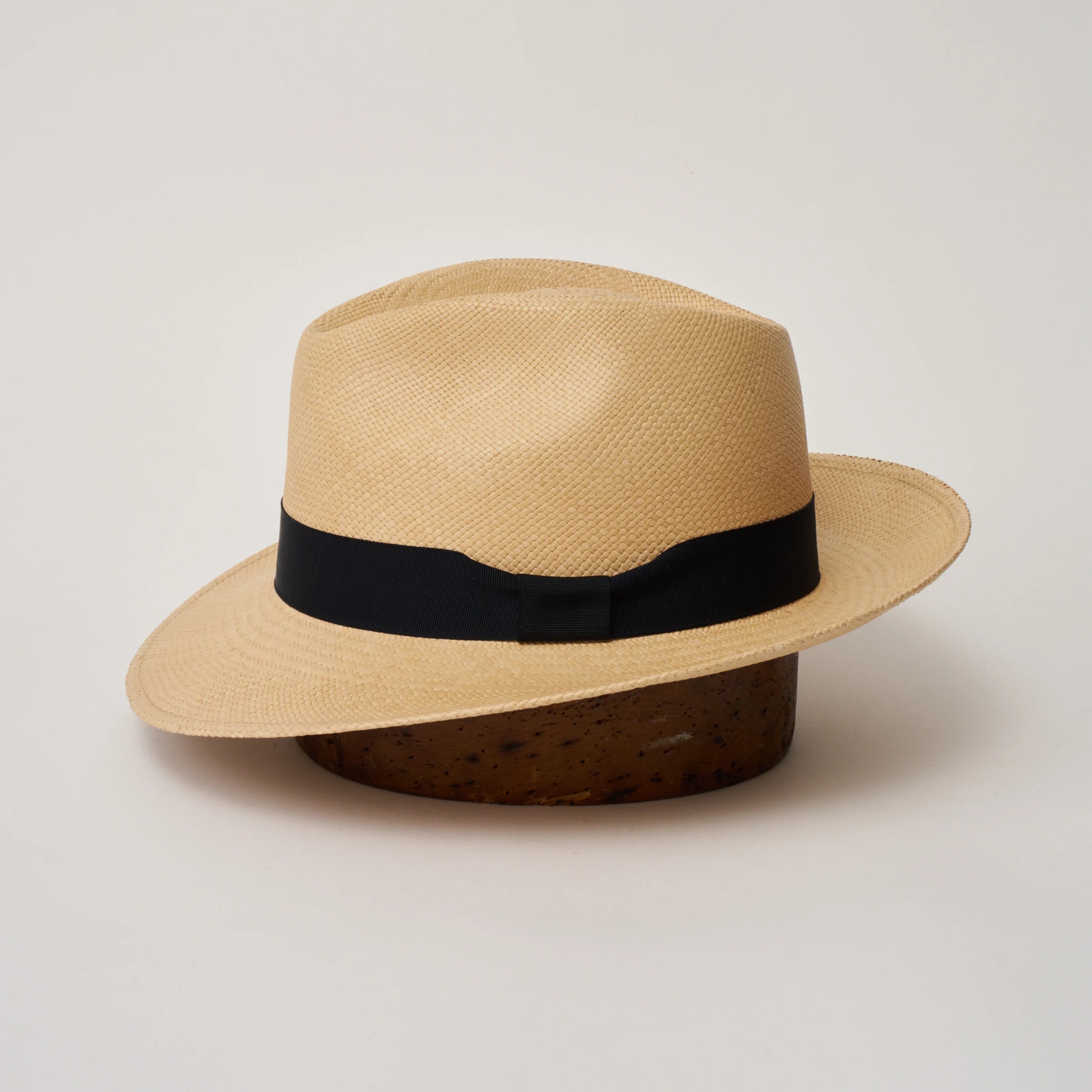 Studio image of the Camilo New Fedora Sand coloured Panama Hat with Marine trim shown from the side, showing the brim shape and ribbon finish.