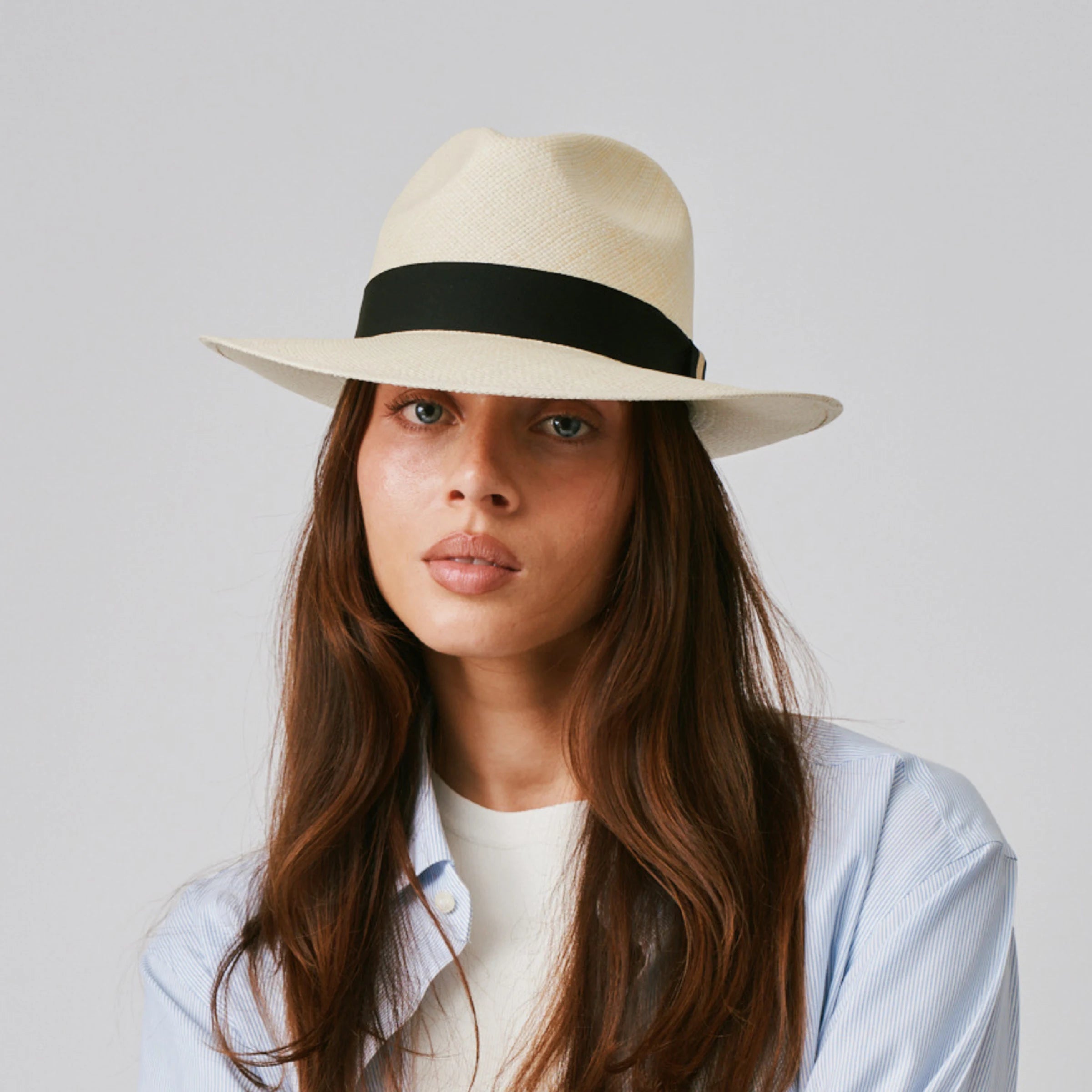 Woman wearing a Camilo Classic Natural / Black Panama hat and a blue shirt against a plain background.