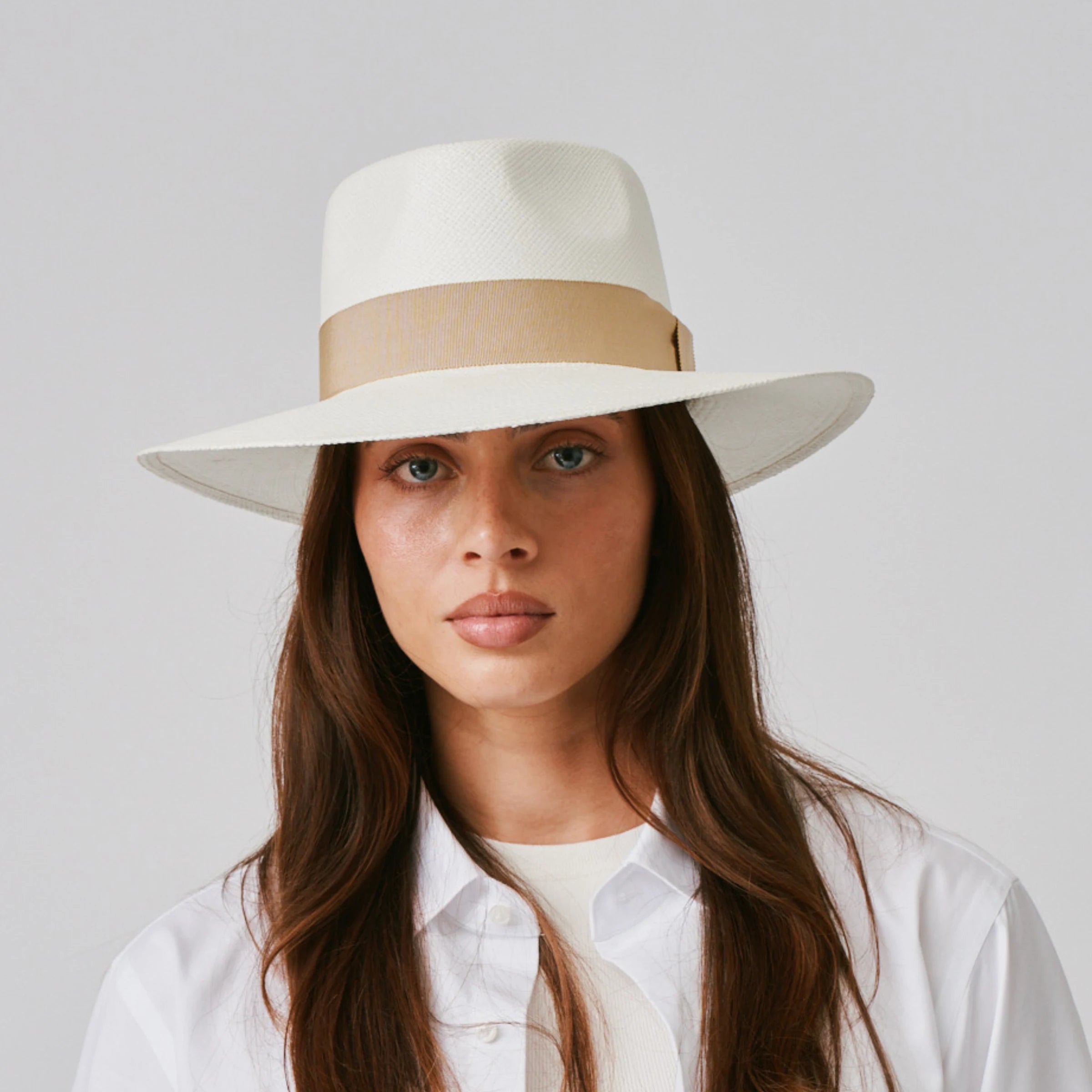 Woman wearing a Country Cream / Camel Panama hat and white shirt against a plain background.
