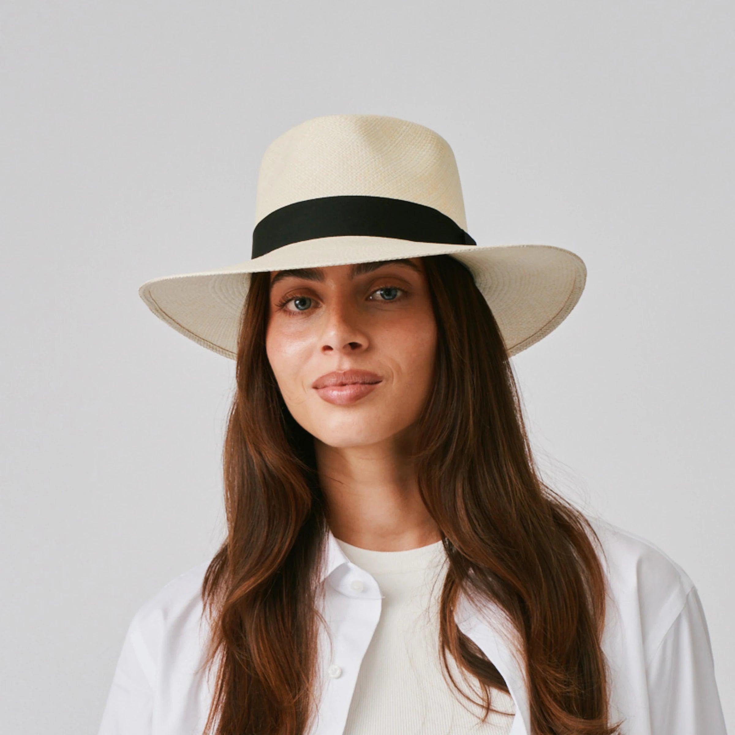 Woman wearing a Country Natural / Black Panama hat and white shirt against a plain background.