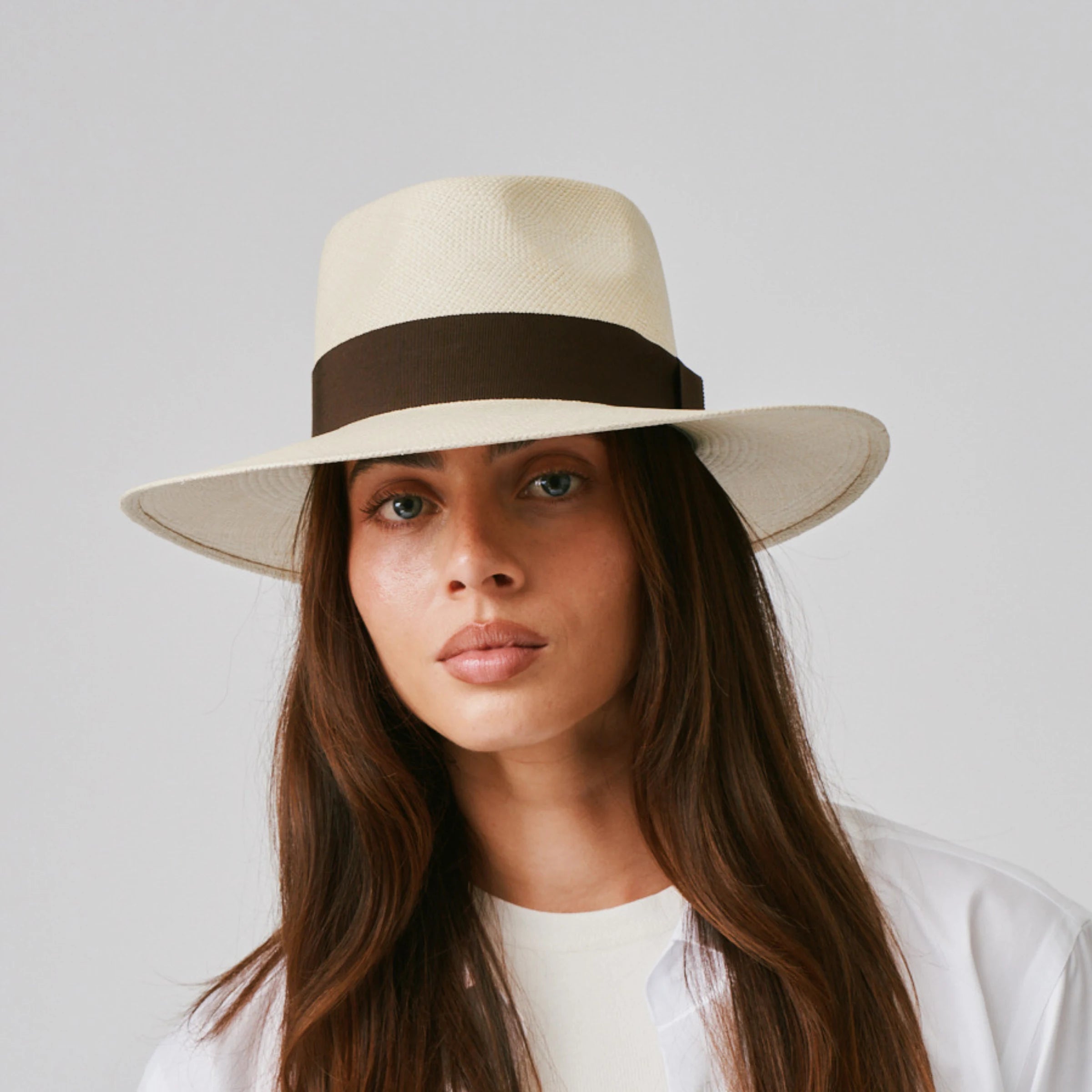 Woman wearing a Country Natural / Chocolate Panama hat and white tee against a plain background.