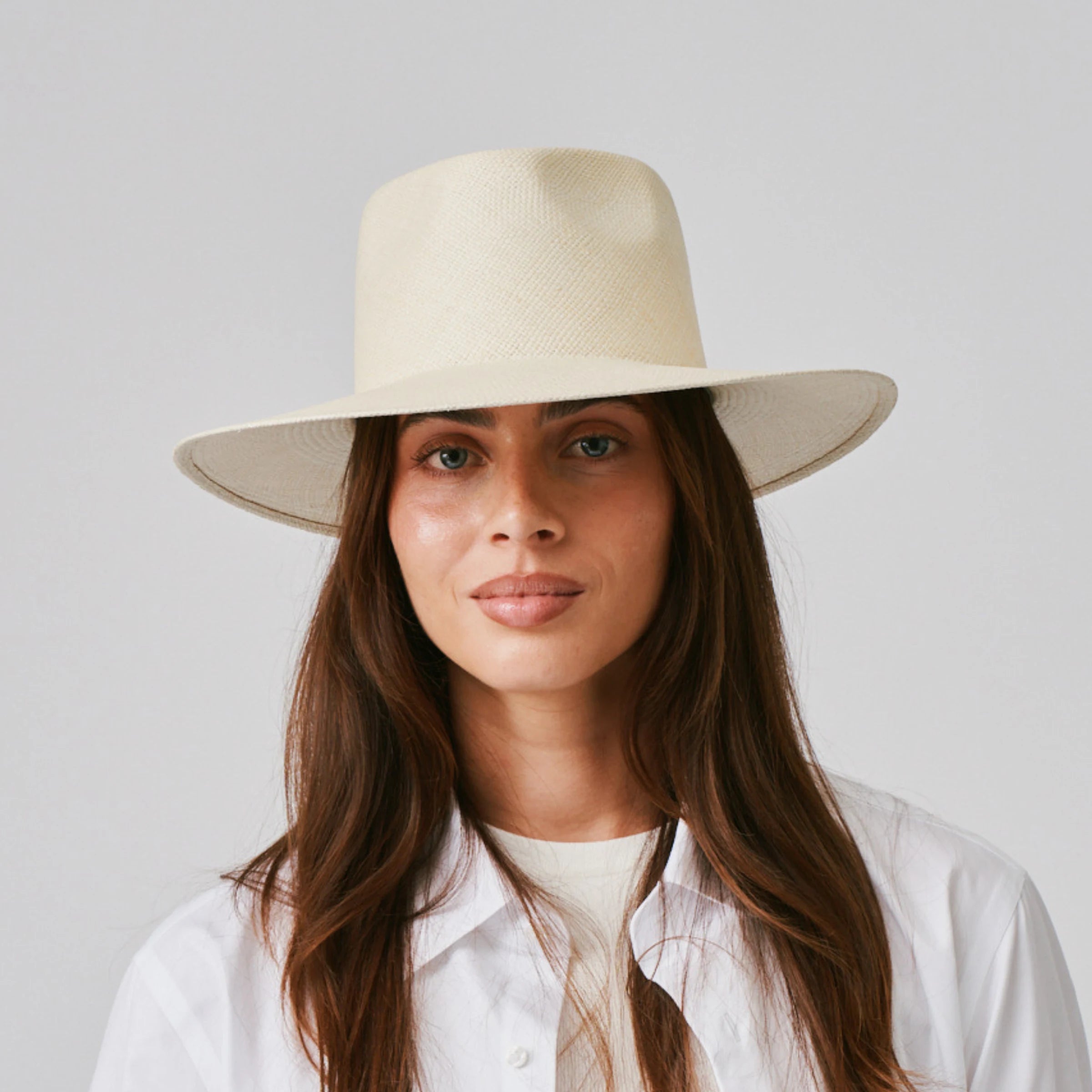Woman wearing a Country Natural Panama hat and white shirt against a plain background.