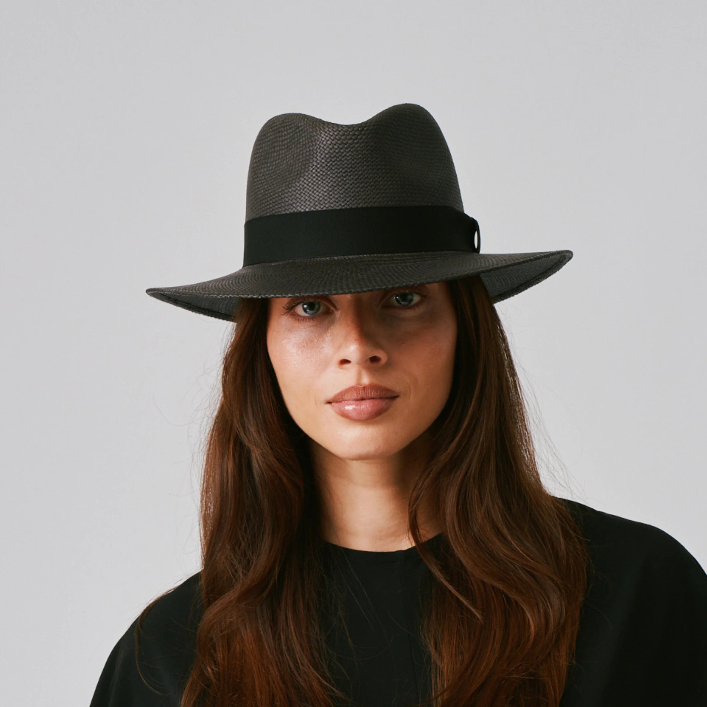 Woman wearing a Executive Black / Black Panama hat and a black top against a plain background.