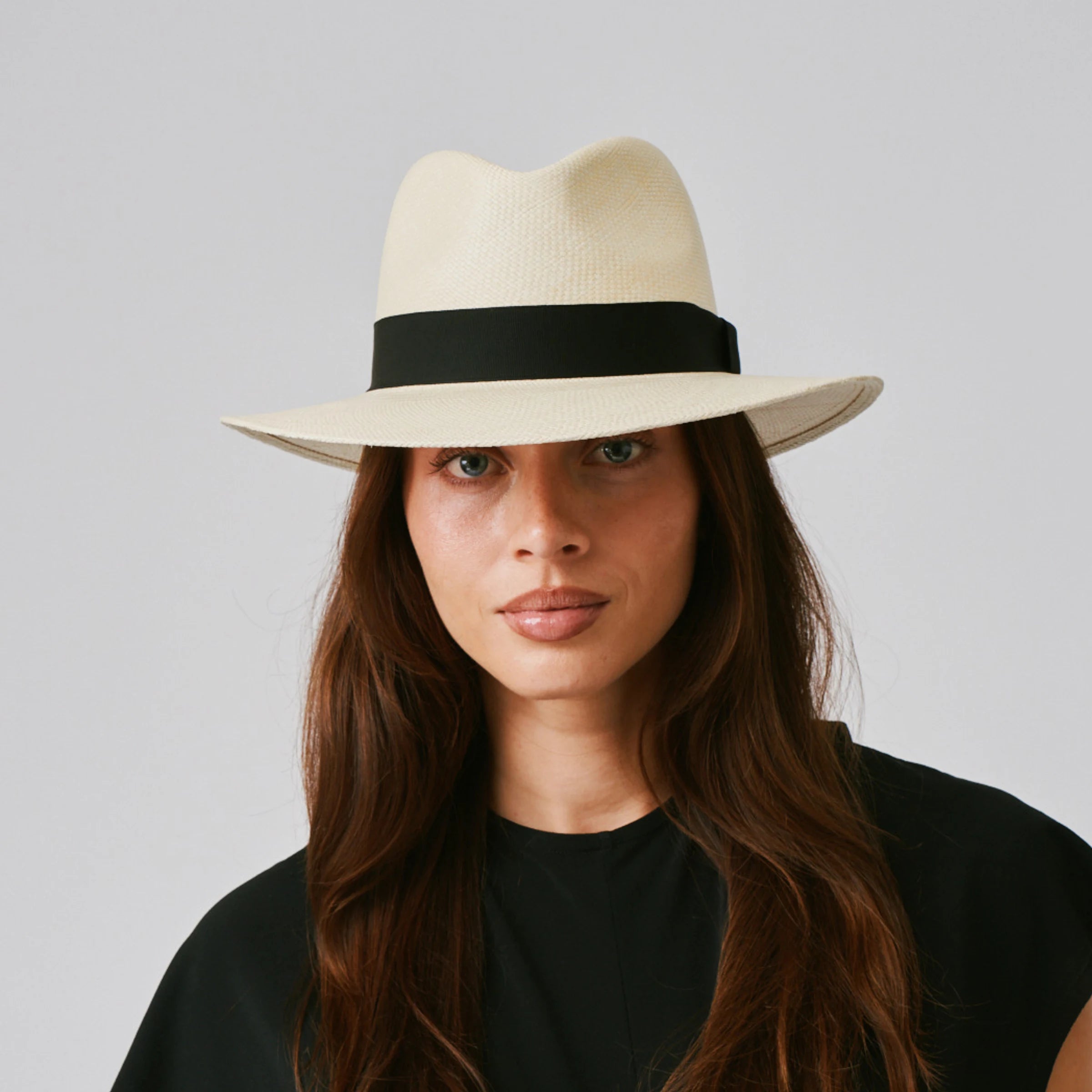 Woman wearing a Executive Natural / Black Panama hat and black top against a plain background.