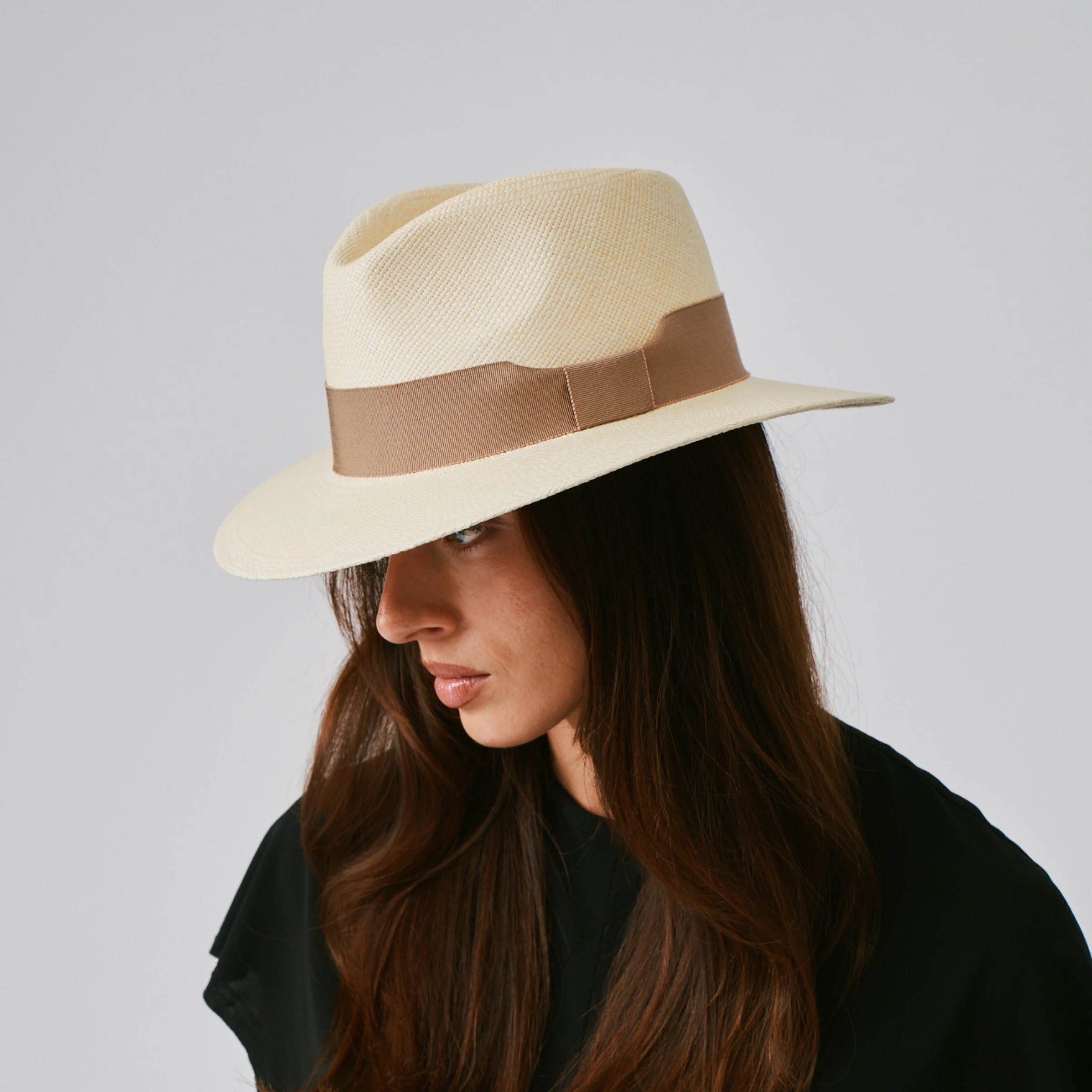 Woman wearing a Executive Natural / Oat Panama hat against a plain background.