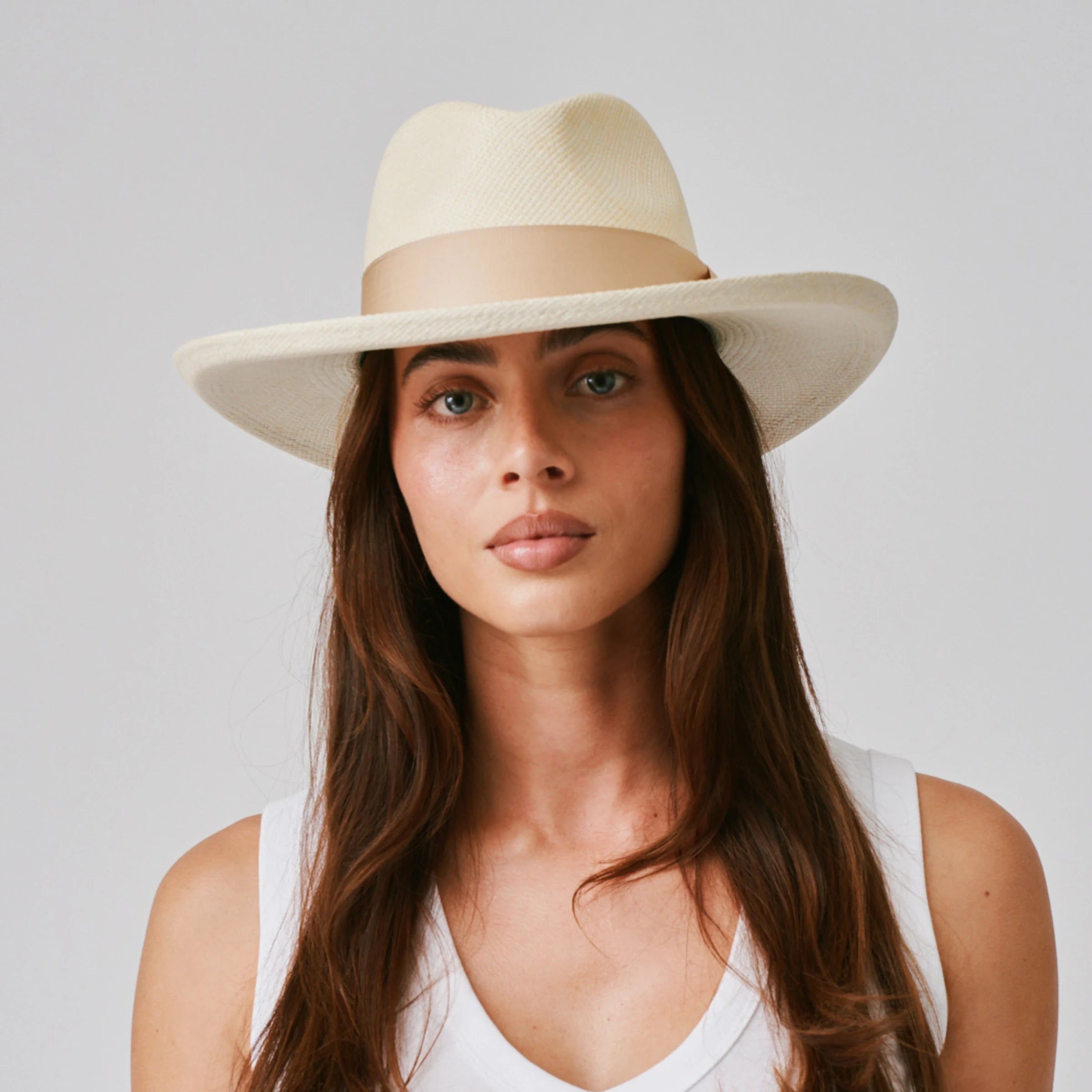 Woman wearing a Grand Planter Natural / Bone Panama hat and white singlet against a plain background.