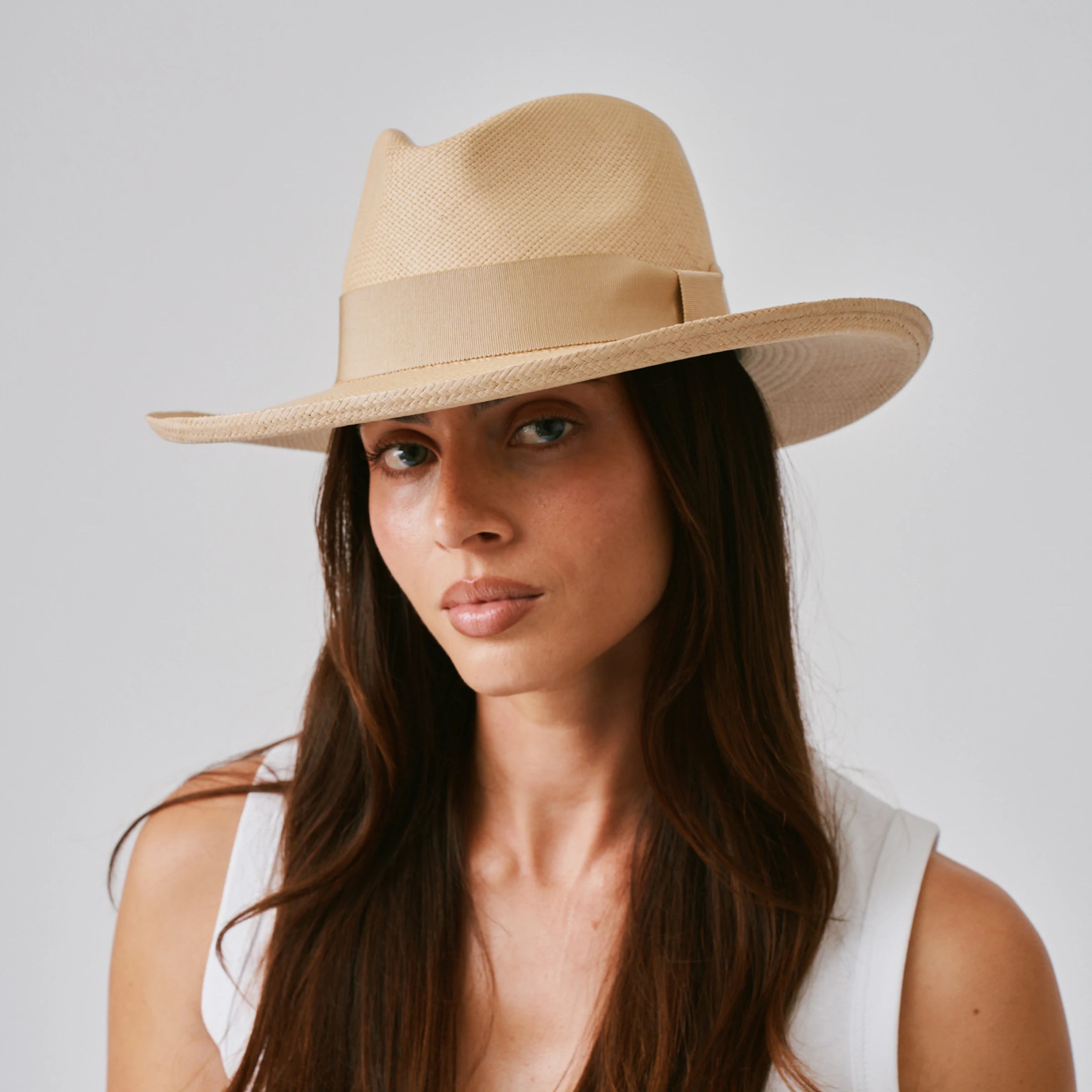 Woman wearing a Grand Planter Sand / Camel Panama hat against a plain background.