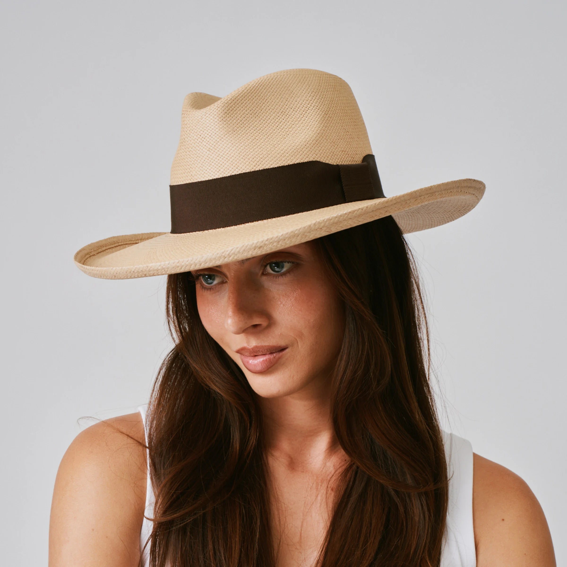 Woman wearing a Grand Planter Sand / Chocolate Panama hat against a plain background.