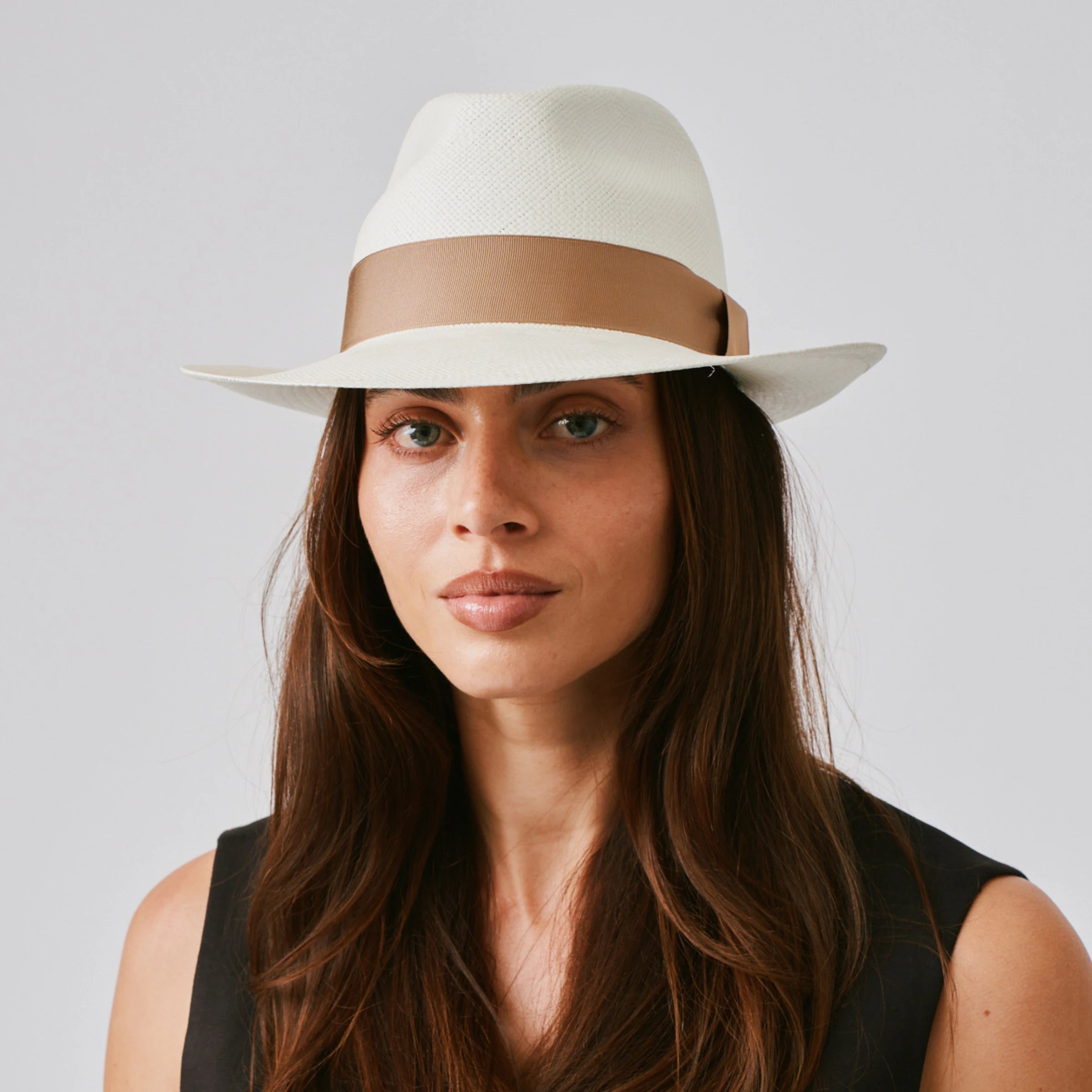 Woman wearing a New Fedora Cream / Tan Panama hat and white singlet against a plain background.