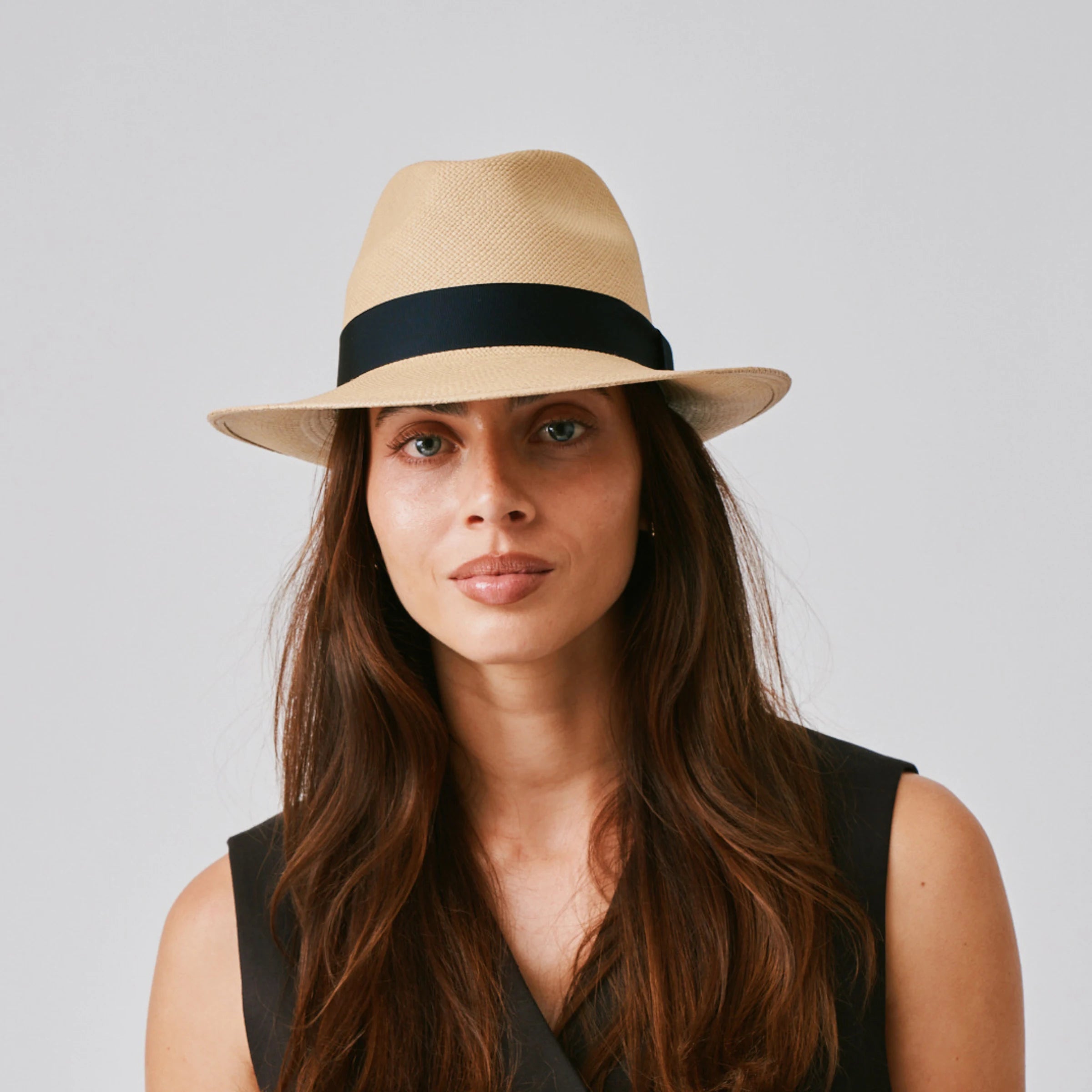 Woman wearing a New Fedora Sand / Marine Panama hat and black top against a plain background.