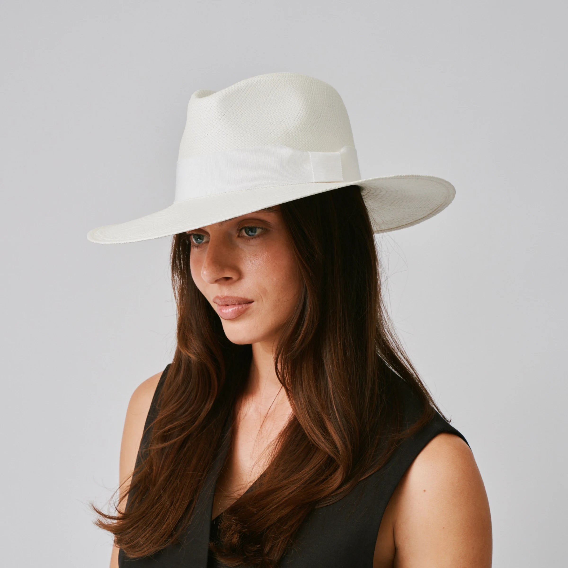Woman wearing a Oro Cream / White Panama hat against a plain background.