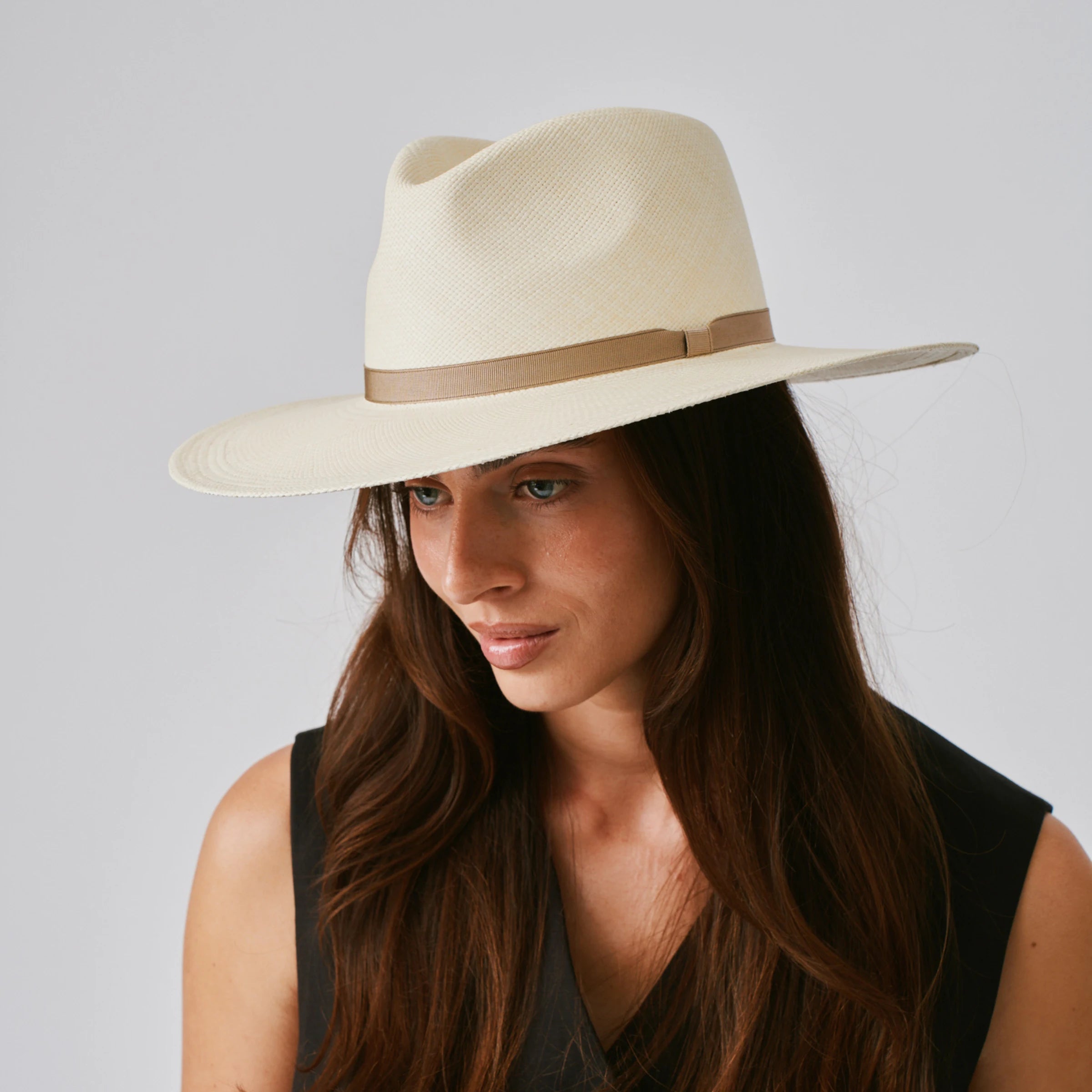 Woman wearing a Oro Natural / Taupe Panama hat against a plain background.