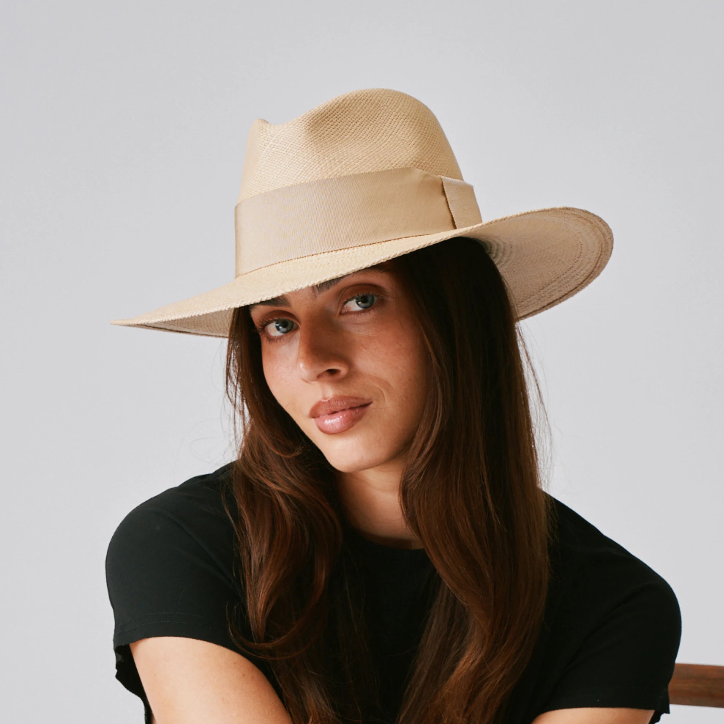 Woman wearing a Oro Sand / Camel Panama hat against a plain background.