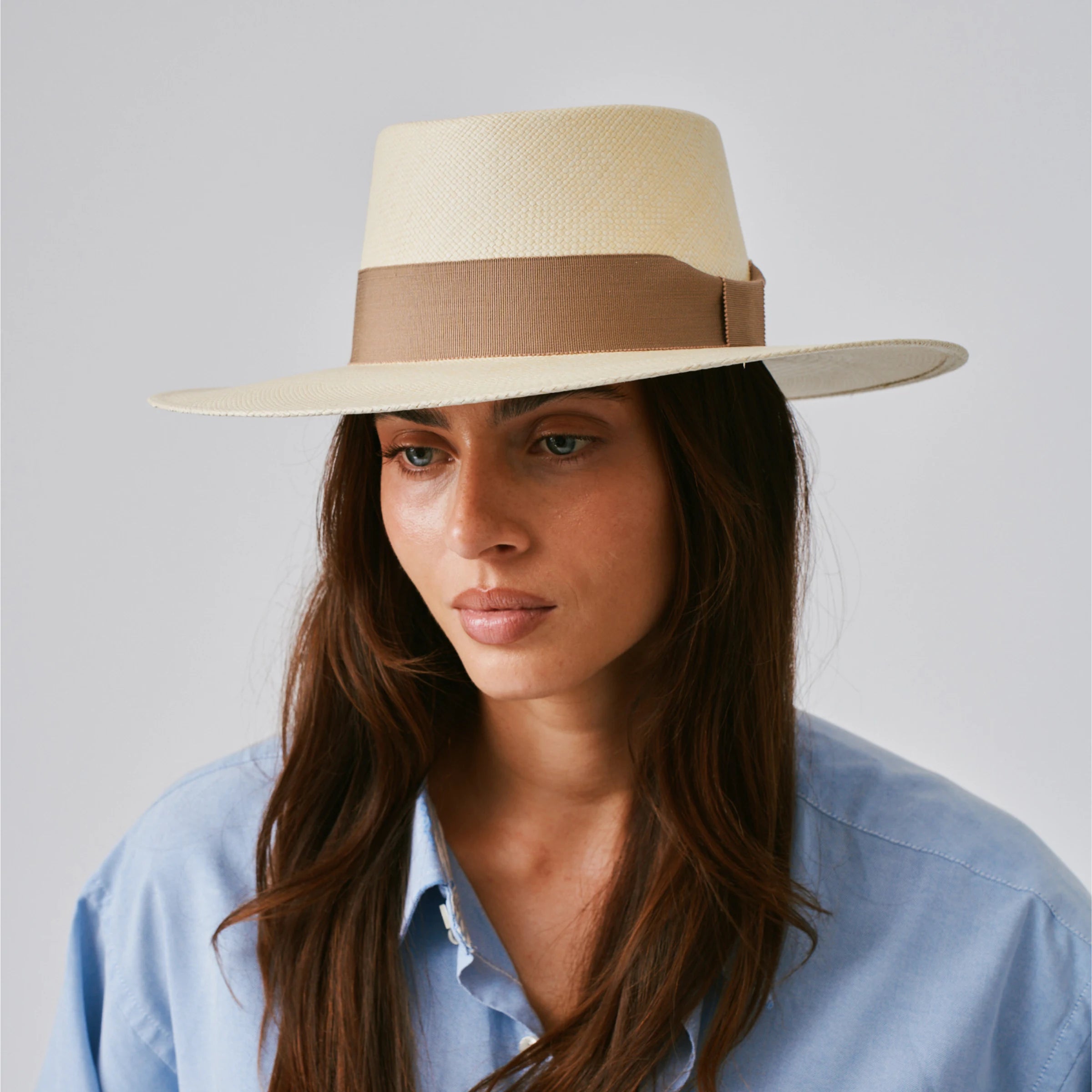 Woman wearing a Sol Natural / Oat Panama hat against a plain background