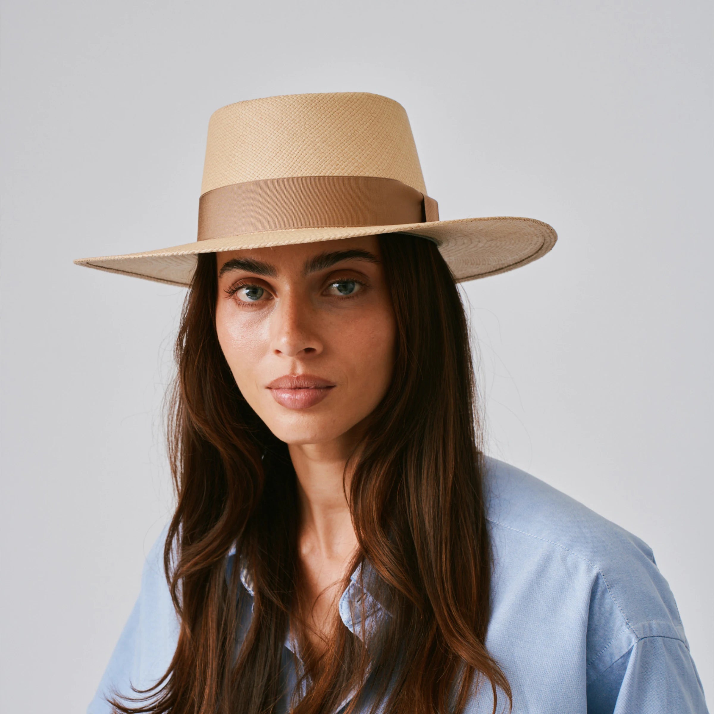 Woman wearing a Sol Sand / Tan Panama hat against a plain background.