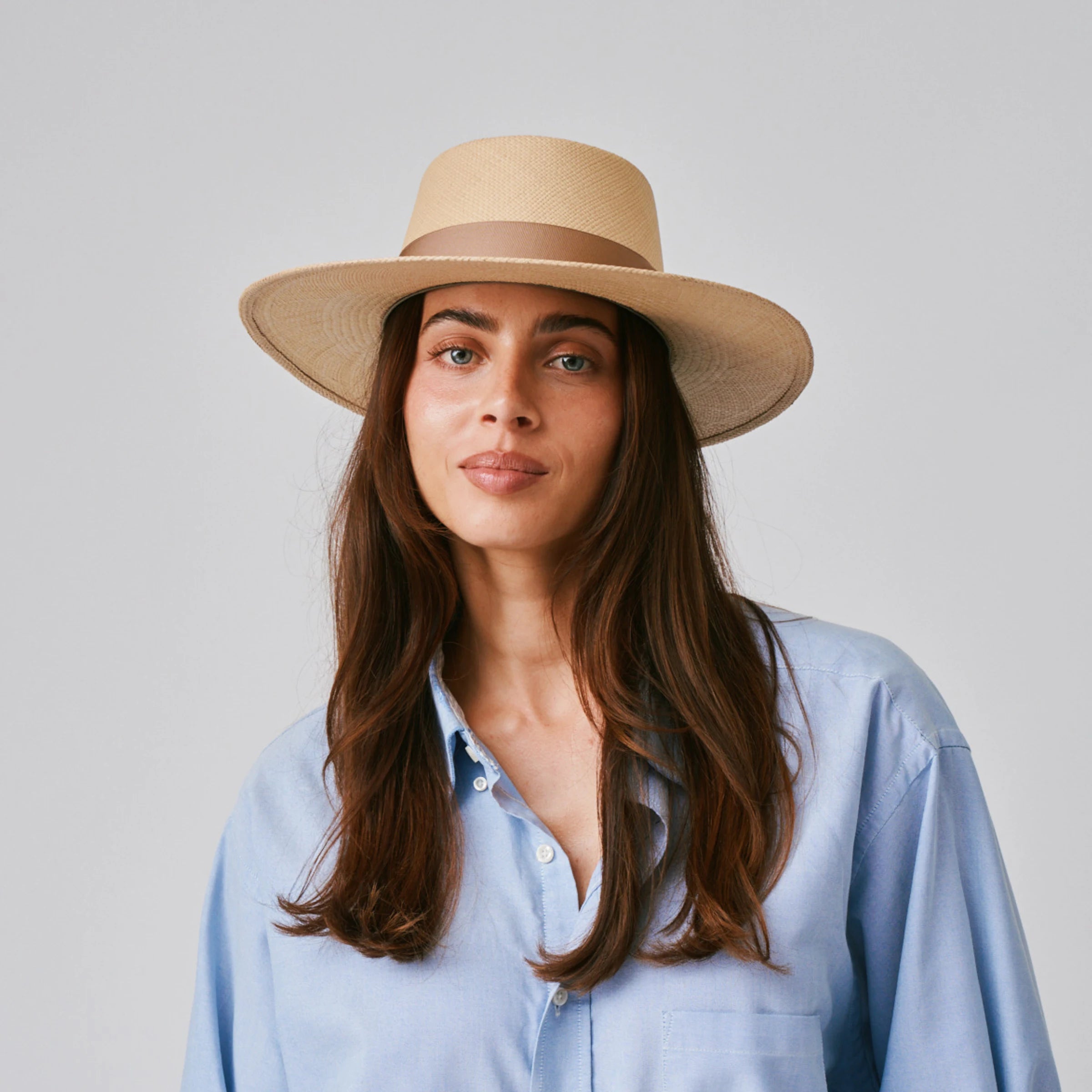 Woman wearing a Sol Sand / Tan Panama hat and blue shirt against a plain background.