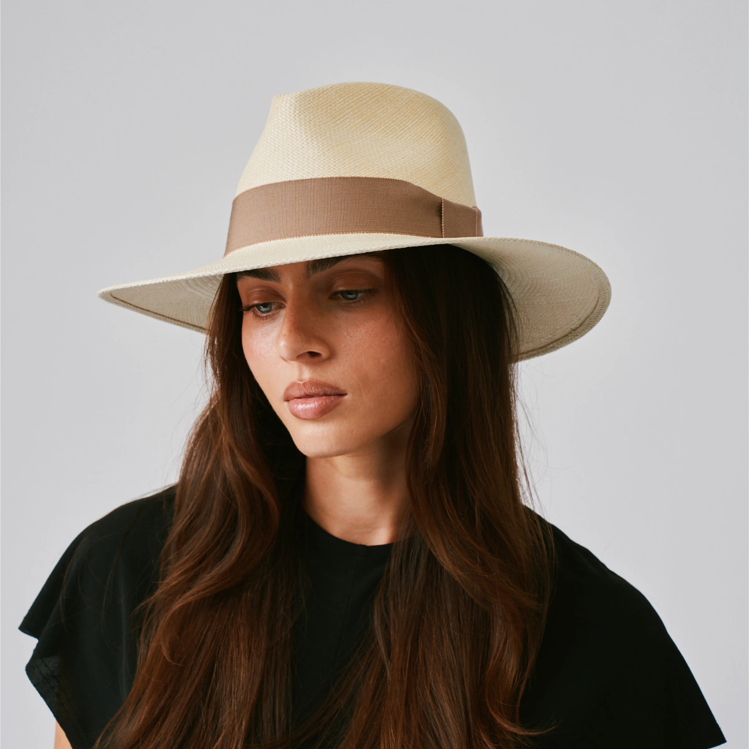 Woman wearing a Vita Natural / Oat Panama hat against a plain background.