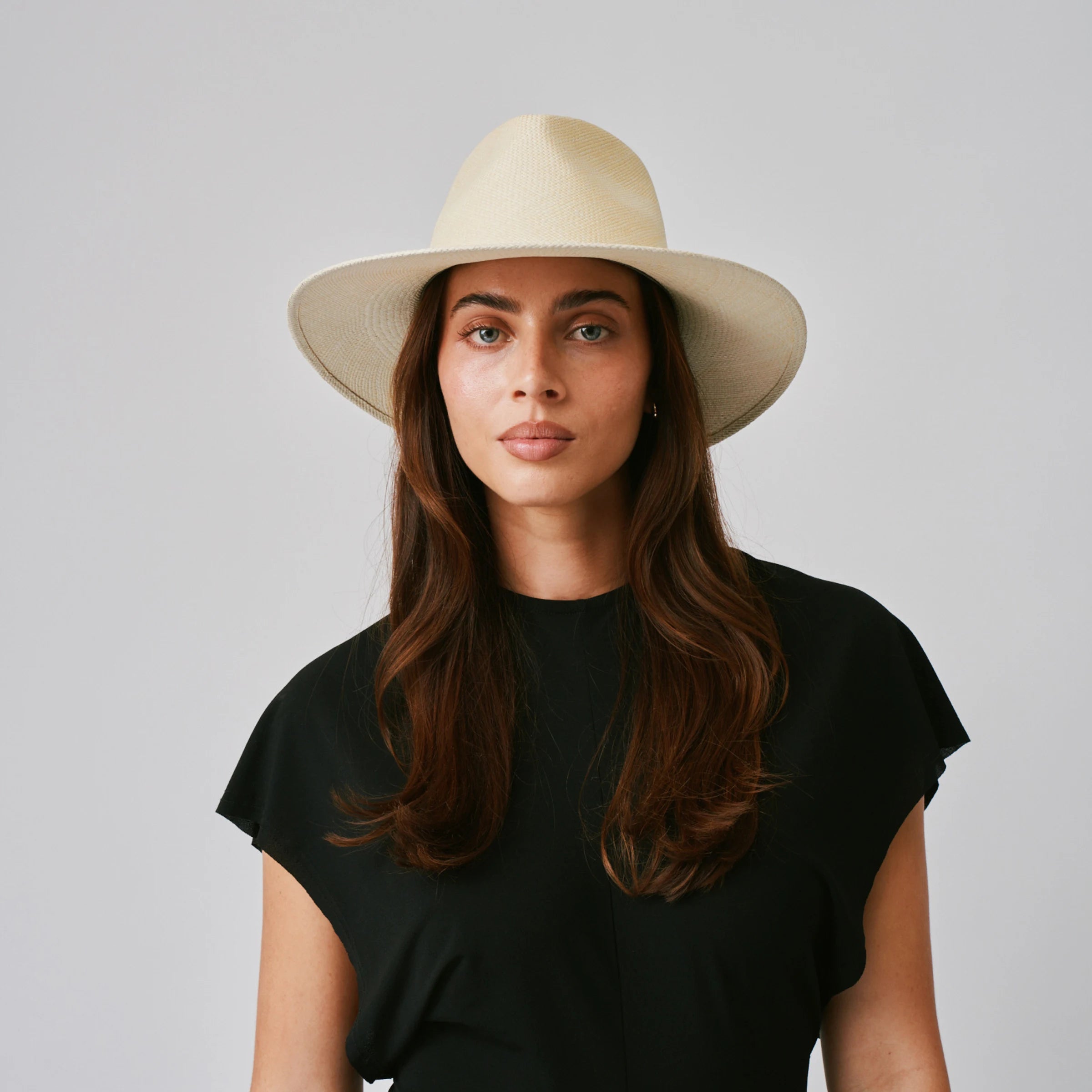 Woman wearing a Vita Natural Panama hat and black top against a plain background.