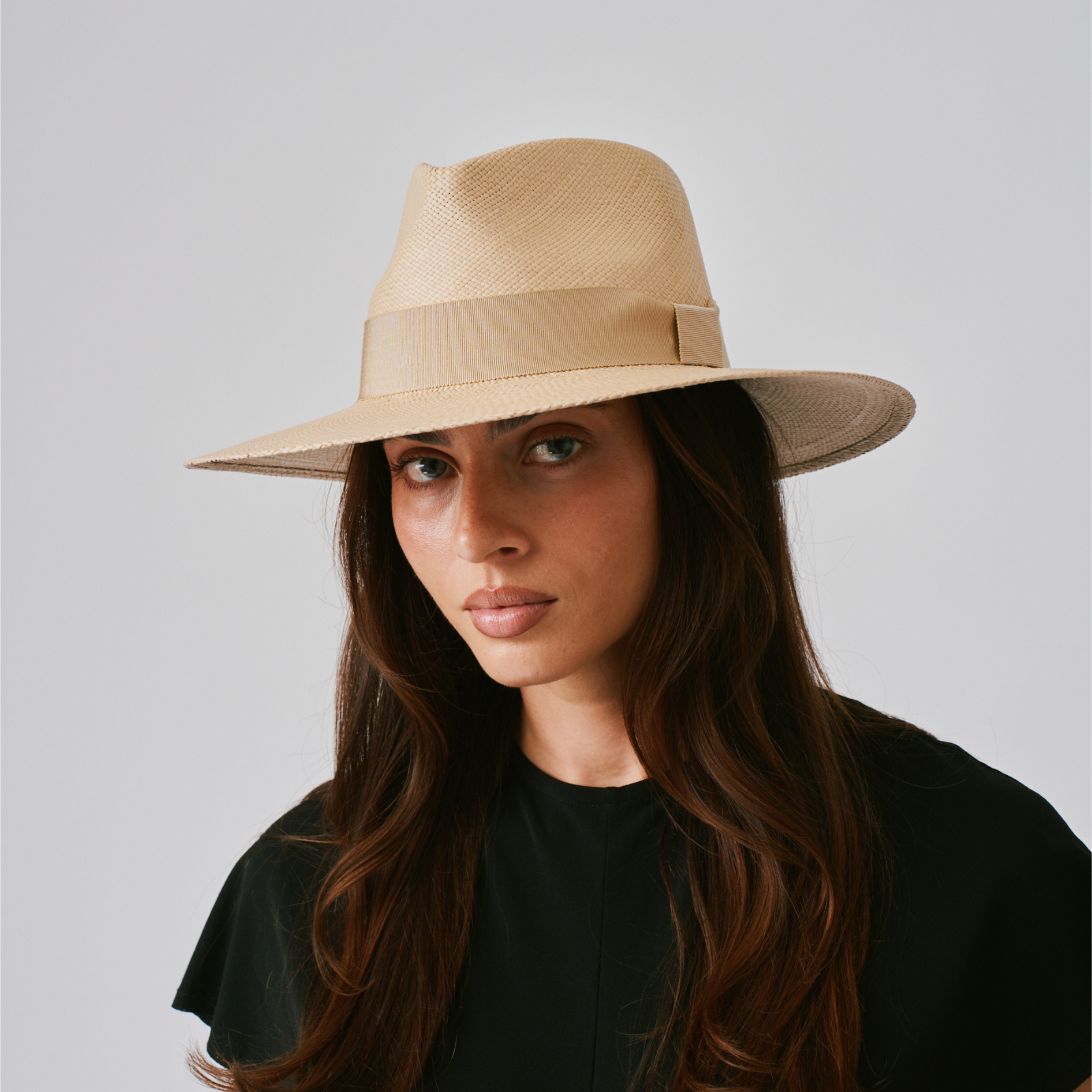 Woman wearing a Vita Sand / Camel Panama hat against a plain background.